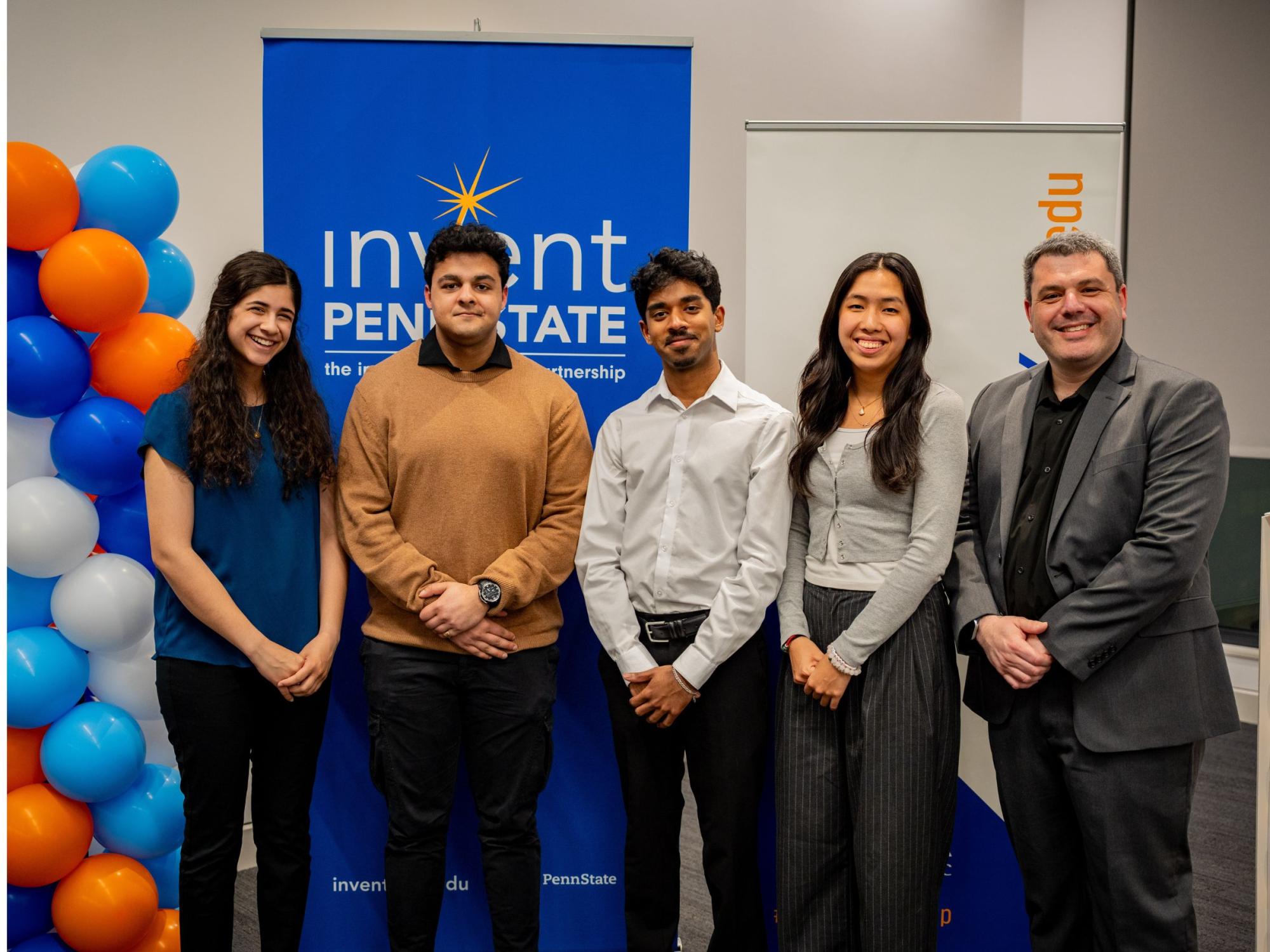 five people standing in front of conference backdrop