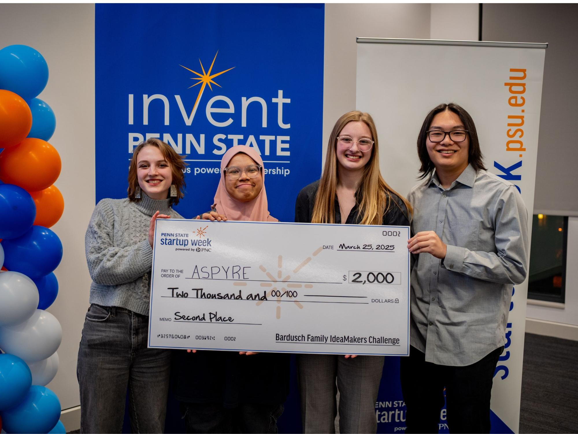 four people display giant check
