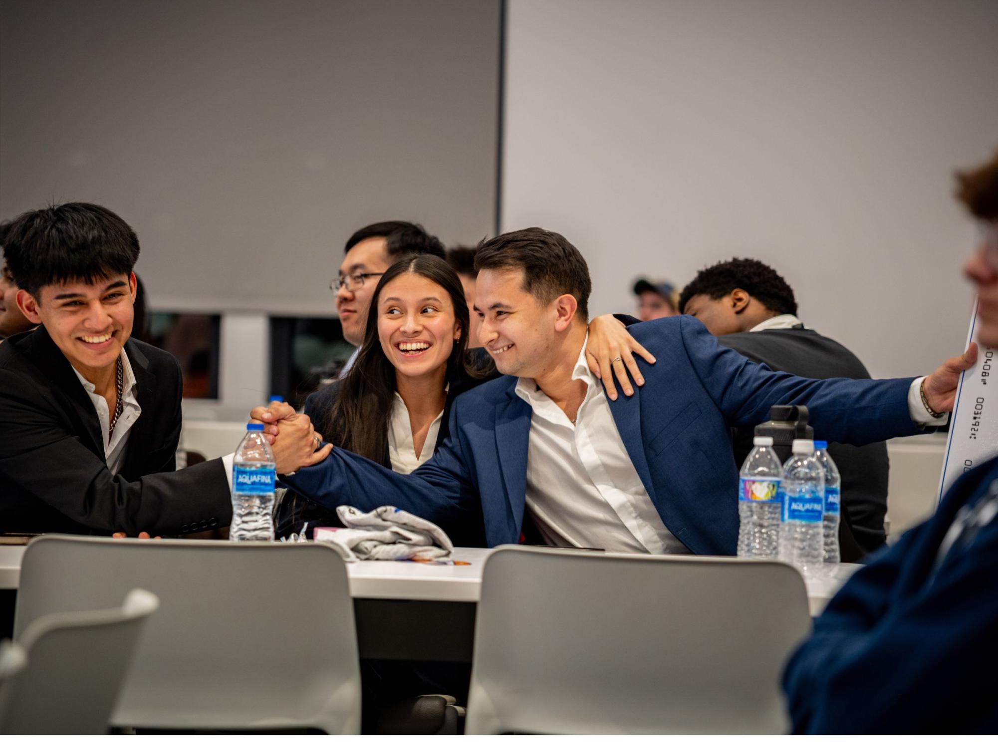 three smiling college students seated at table