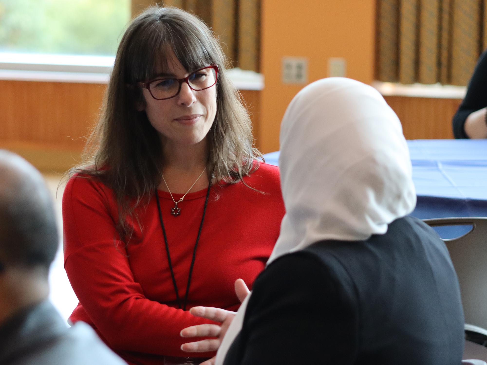 A woman listens to another woman speak in a conference room.
