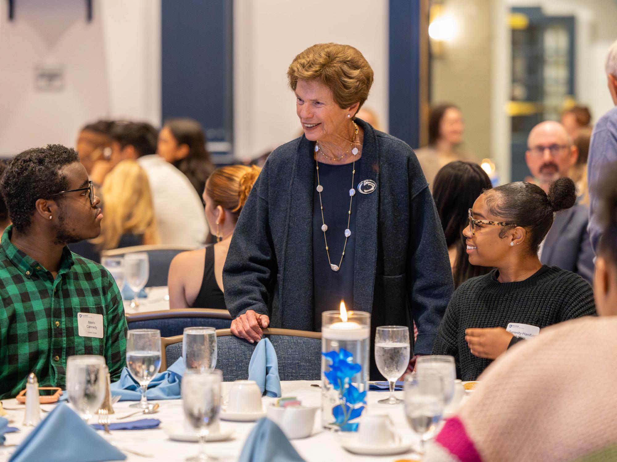 Serenity Myers (right) sits at a table watching as Roz Chaiken (center) interacts with student Mekhi Cannedy (left) who is also seated at the table.