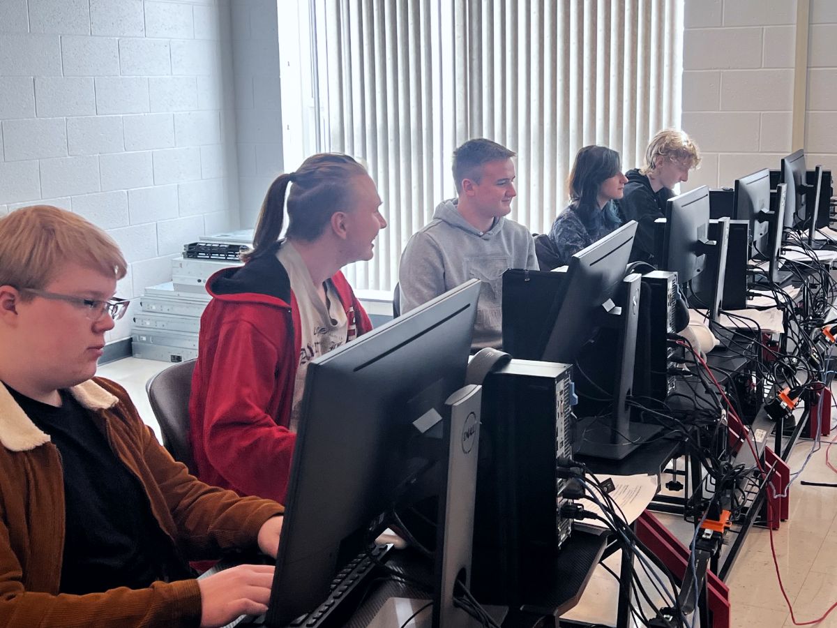 Five students sitting at computers in a computer lab