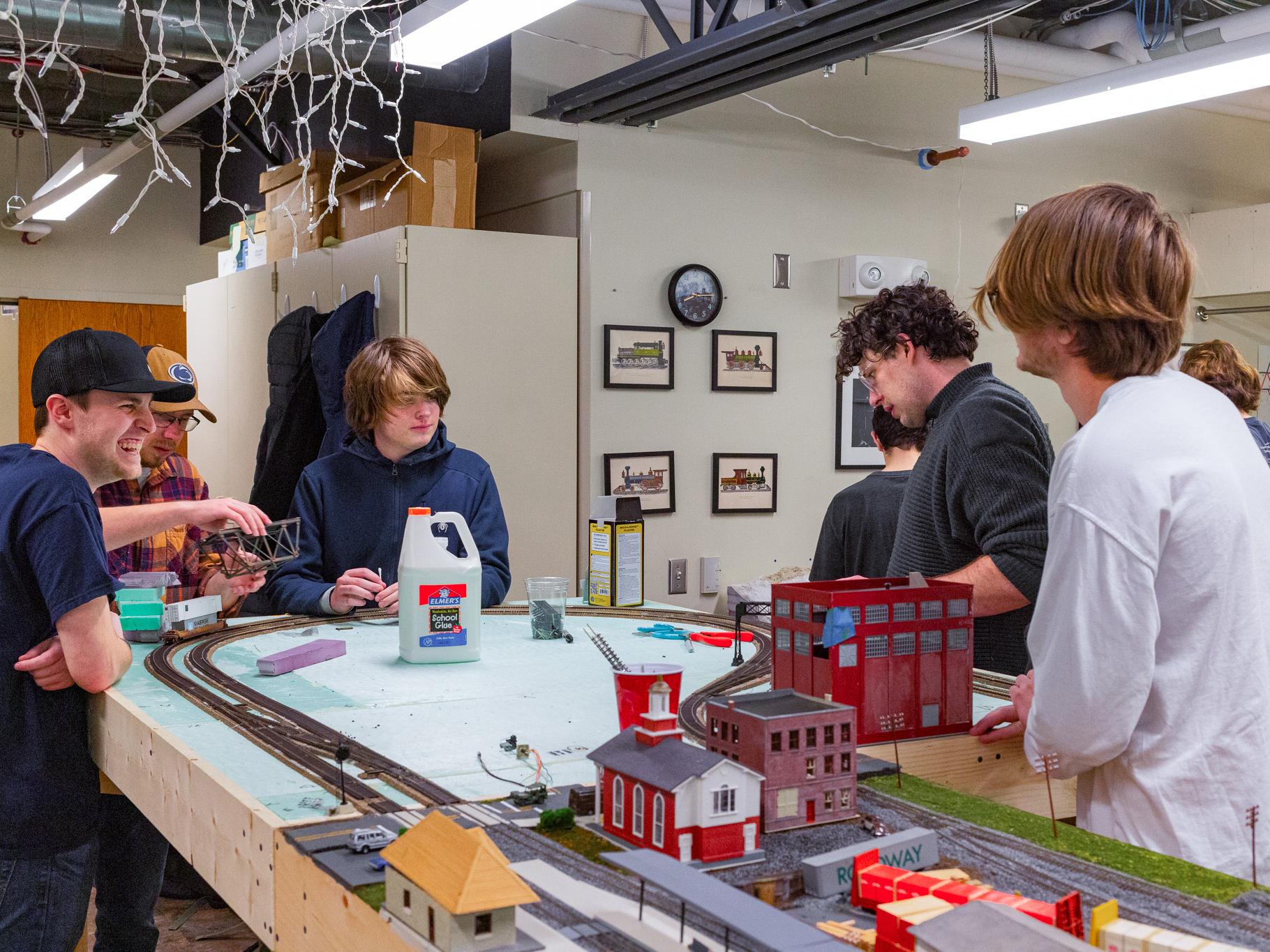 A handful of students gather around a layout of a model railway