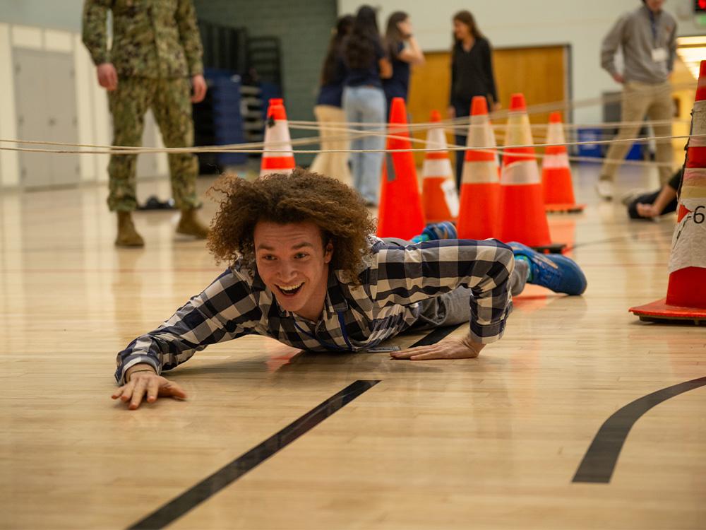 Student crawling on ground.