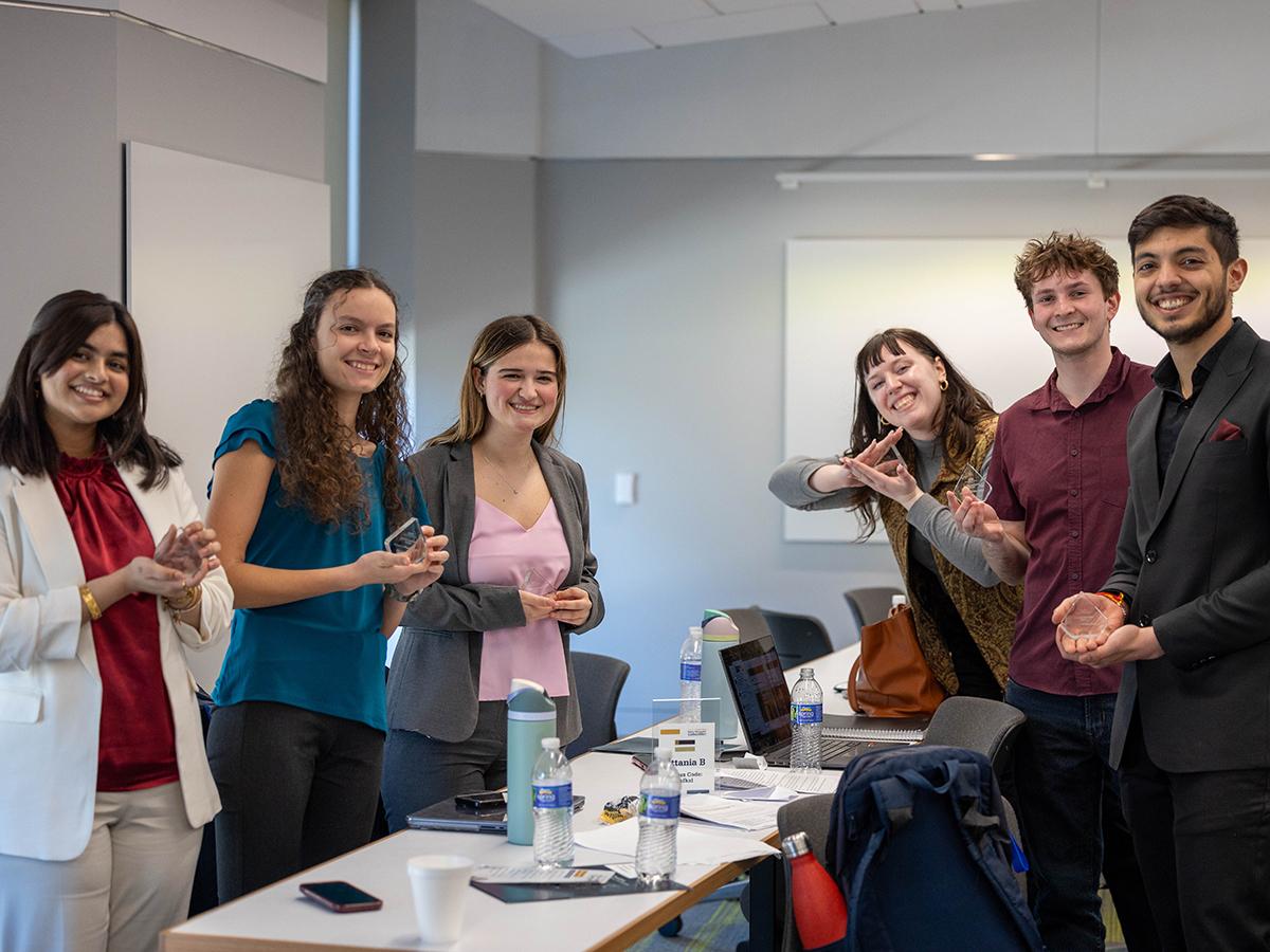 Six students from the winning Policy Simulation Competition team hold up their awards