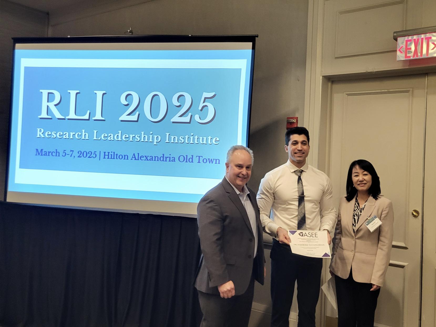 Photo of Fariborz Tavangarian holding an award, standing with two people, near a screen that says RLI 2025