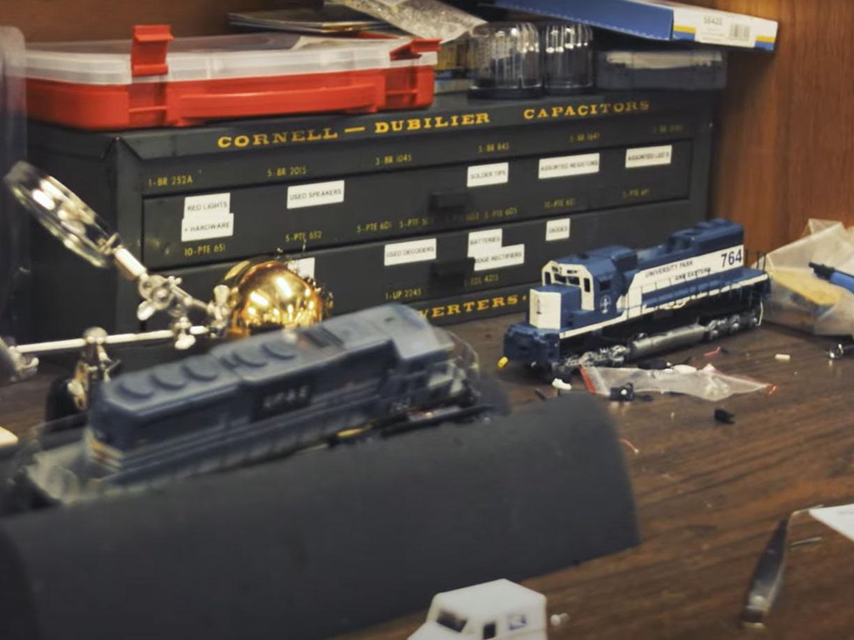A table full of model railway pieces, including one train car painted blue and white