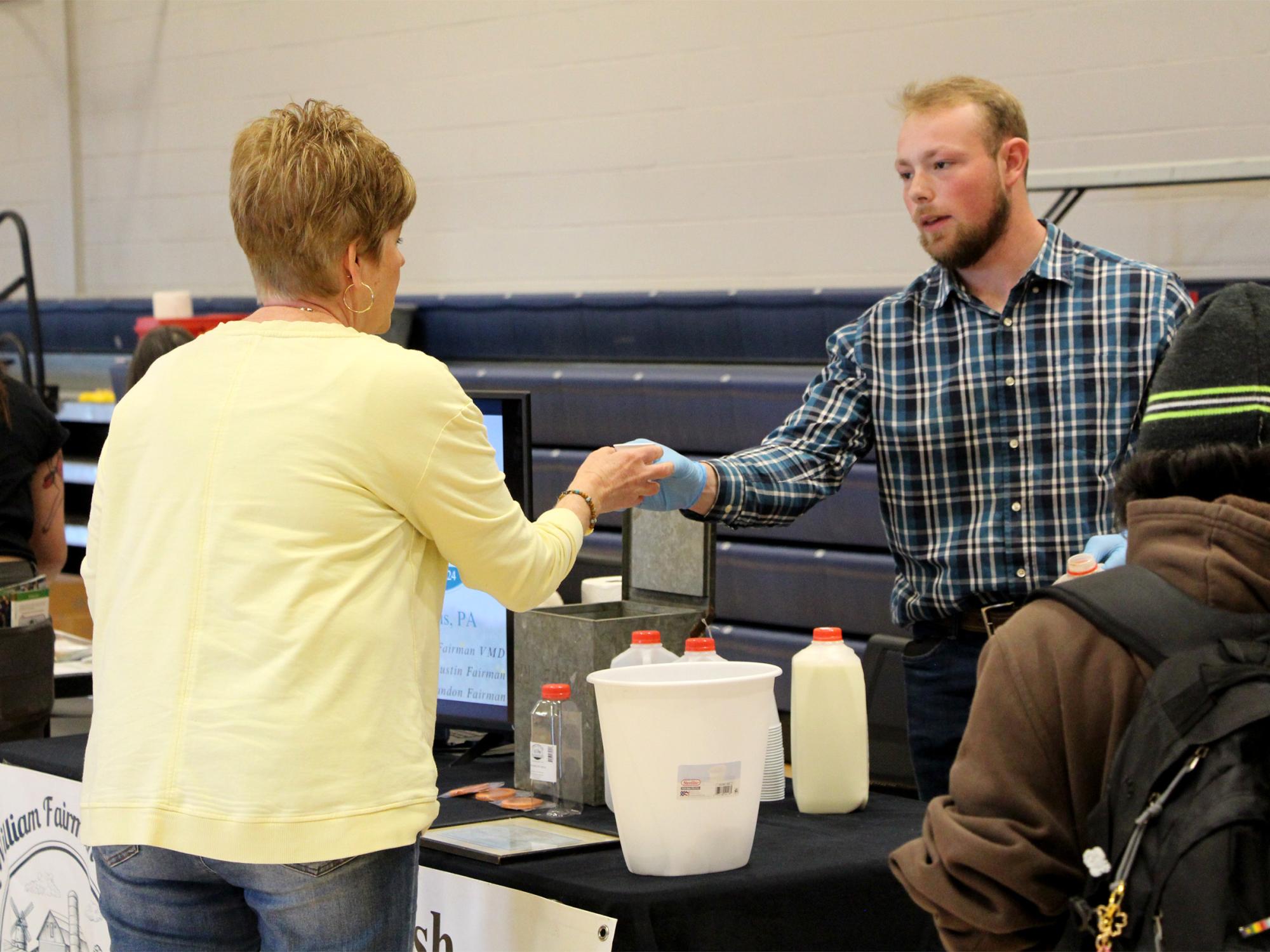 A representative from Fairman Dairy shares a product sample with a visitor during the earth day celebration at Penn State DuBois.