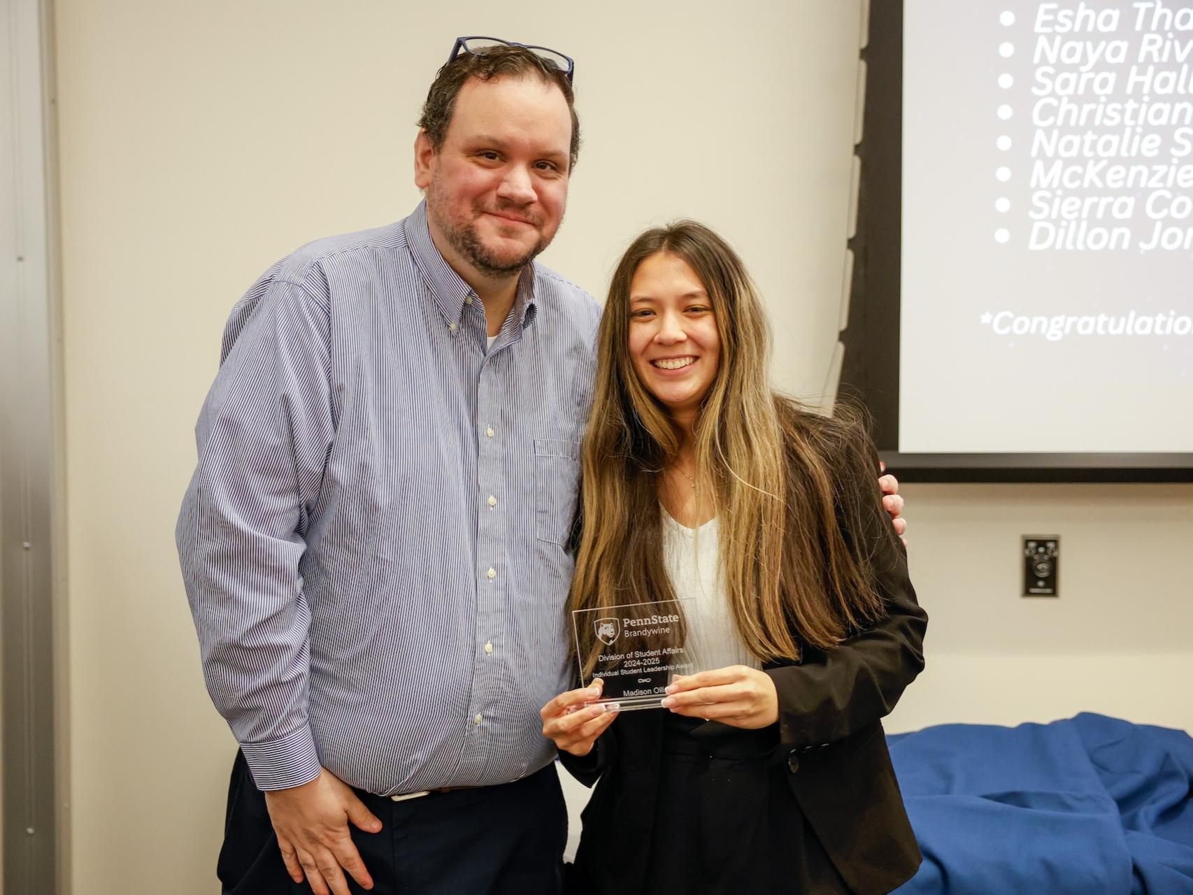 student and staff member with award
