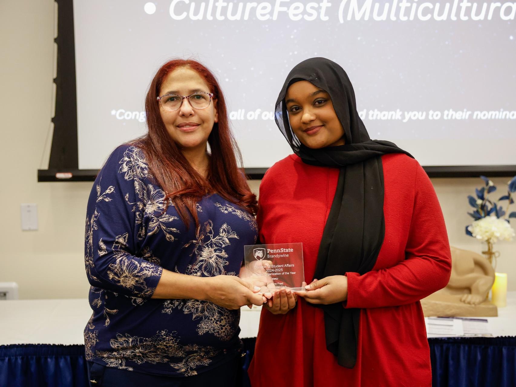 student and staff member with award