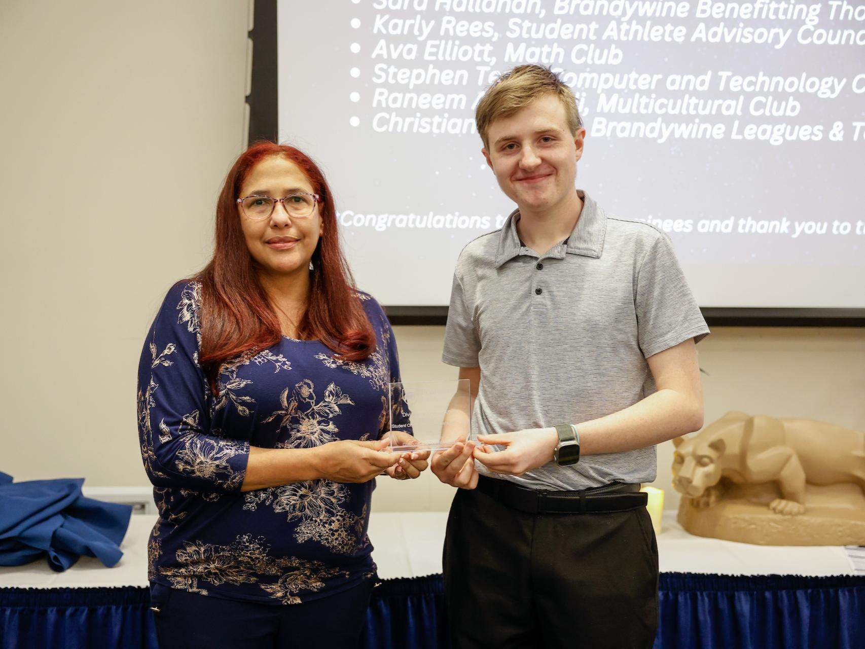 student and staff member with award