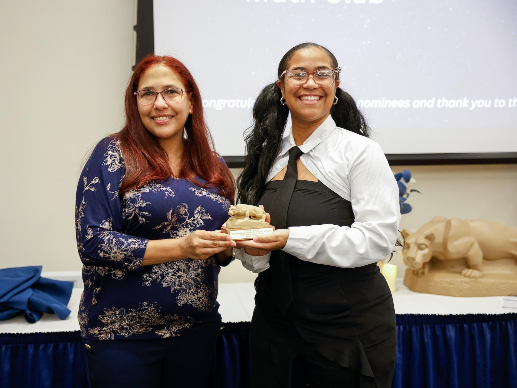student and staff member with award