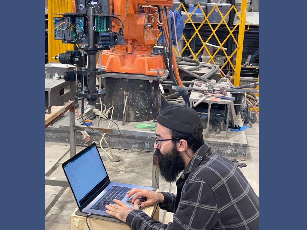 A side profile of Ali Baghi working on a laptop in a lab.