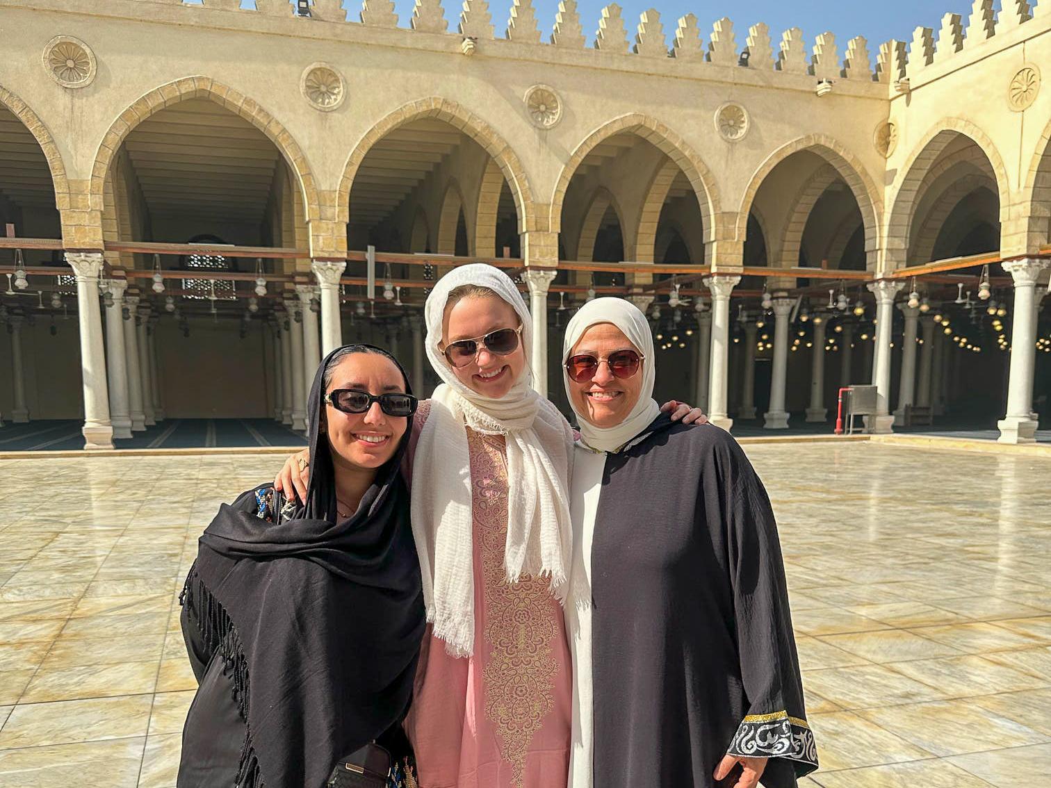 Three Penn State students posed in long robes with head scarves in a white courtyard in Cairo, Egypt.