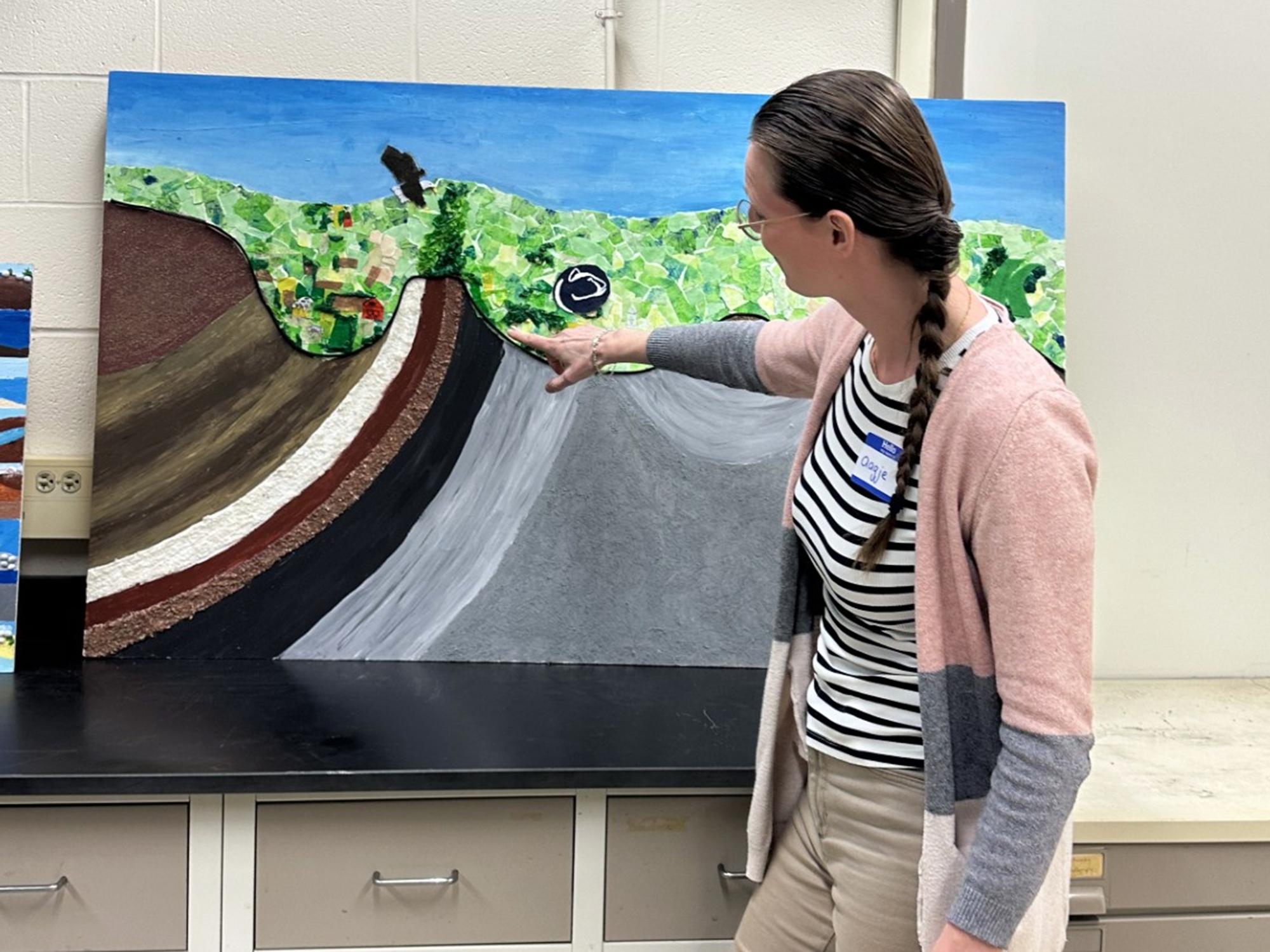 Aagje Eijsink shows off a graphic collage of the Earth's layers during a lesson on sedimentation and sea level. 