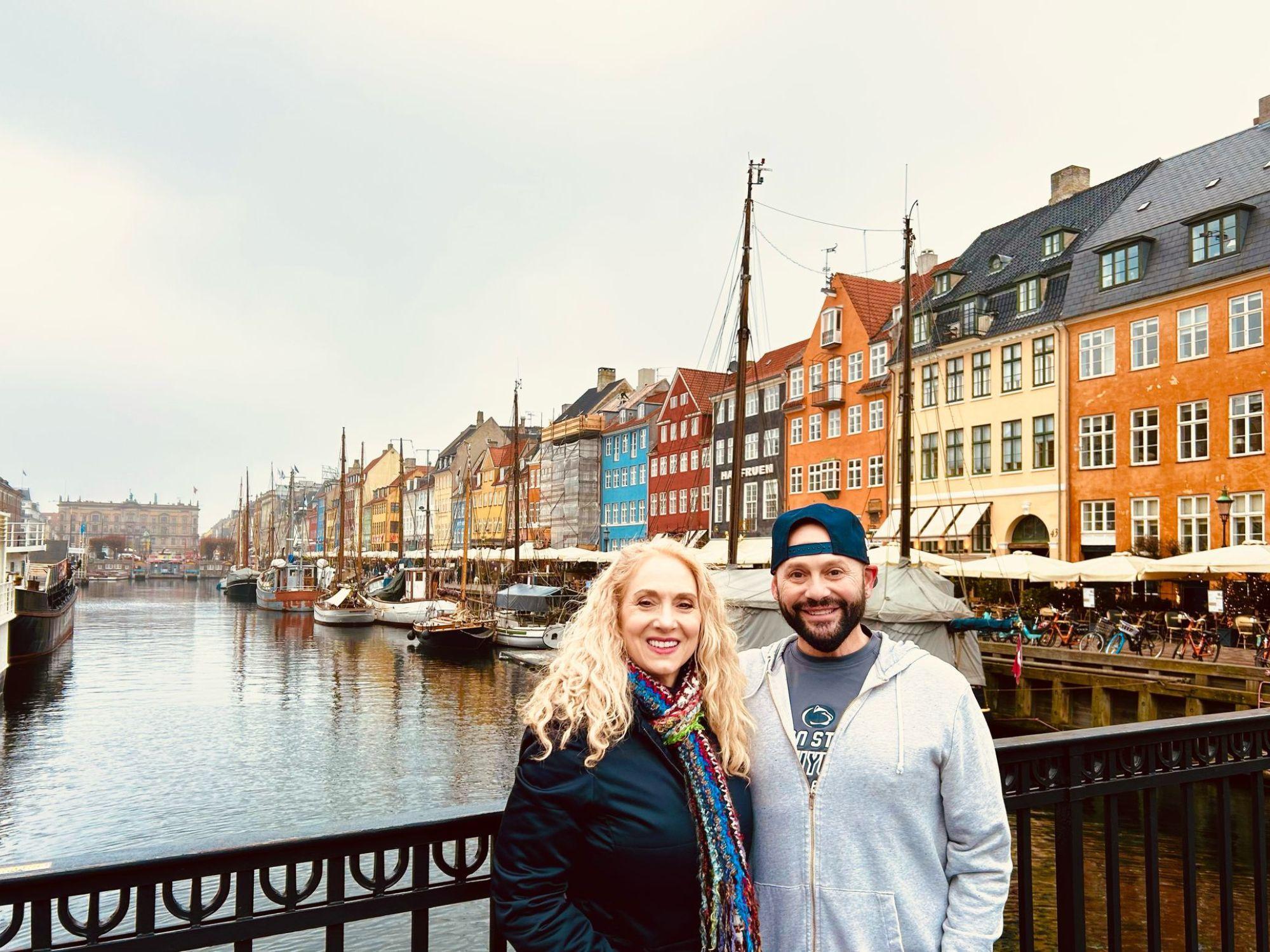 a man and a woman stand against a rail on a bridge over a canal in copenagen