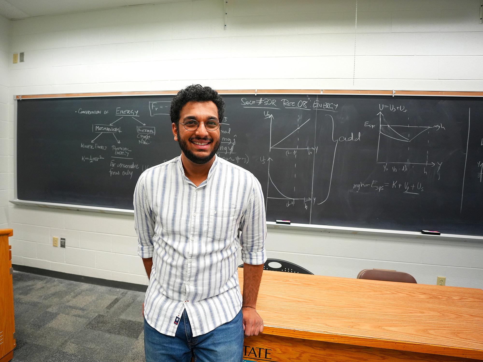 Image of Pranav standing in front of a chalkboard