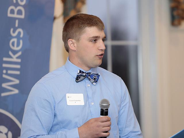 A male student speaking while holding a microphone.