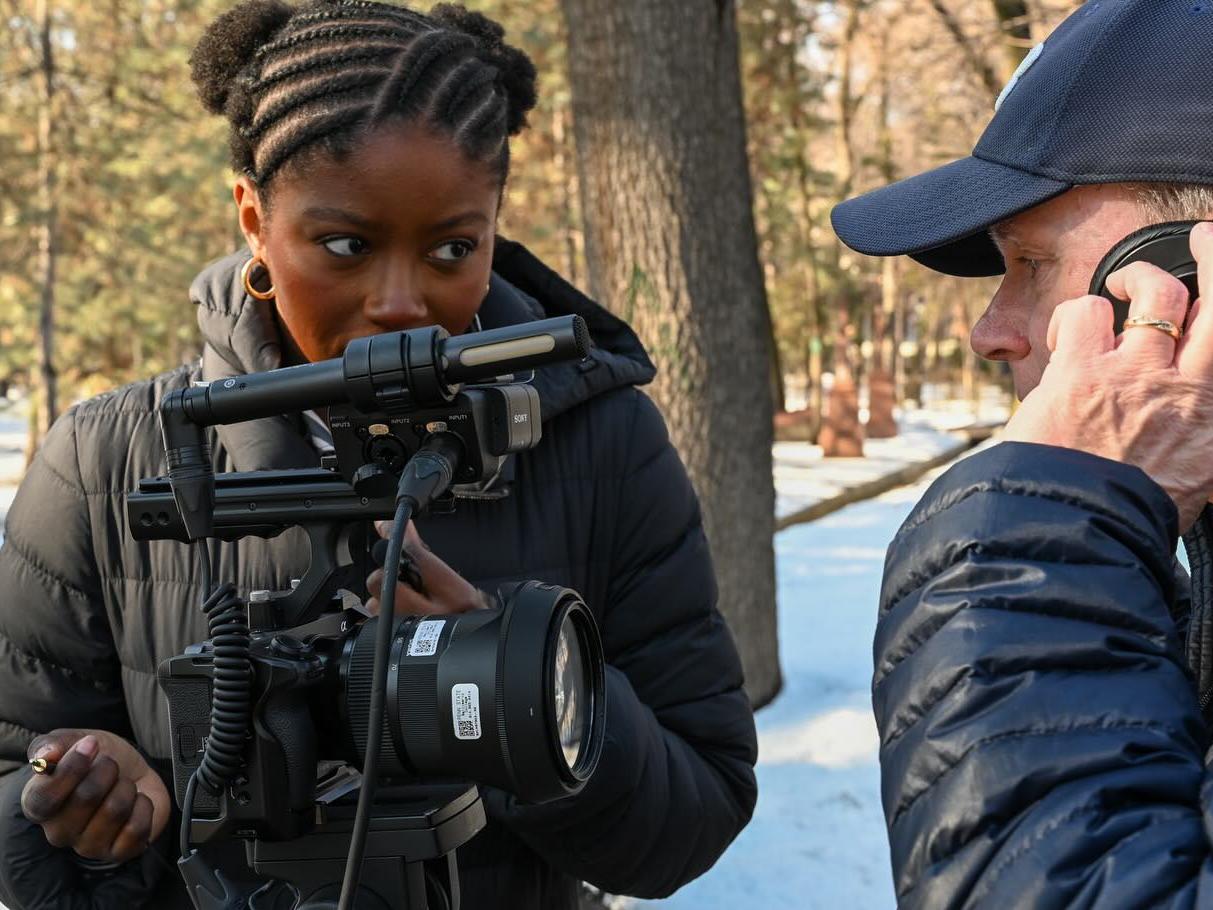A student points a camera at a subject talking on a cell phone