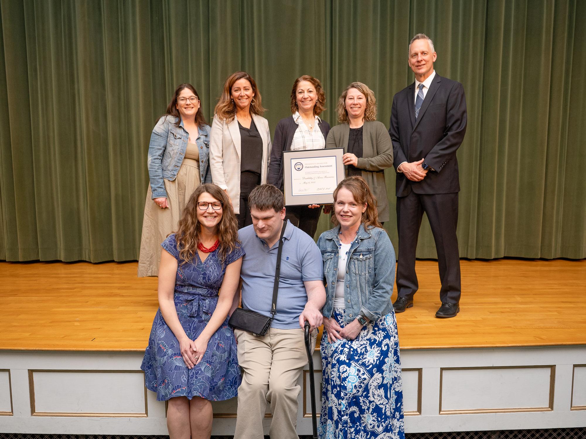 A group of people pose together on an auditorium stage