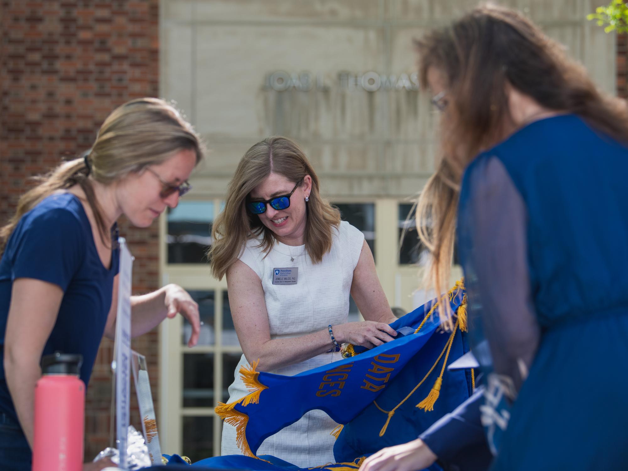 Three women lean over a table of banners