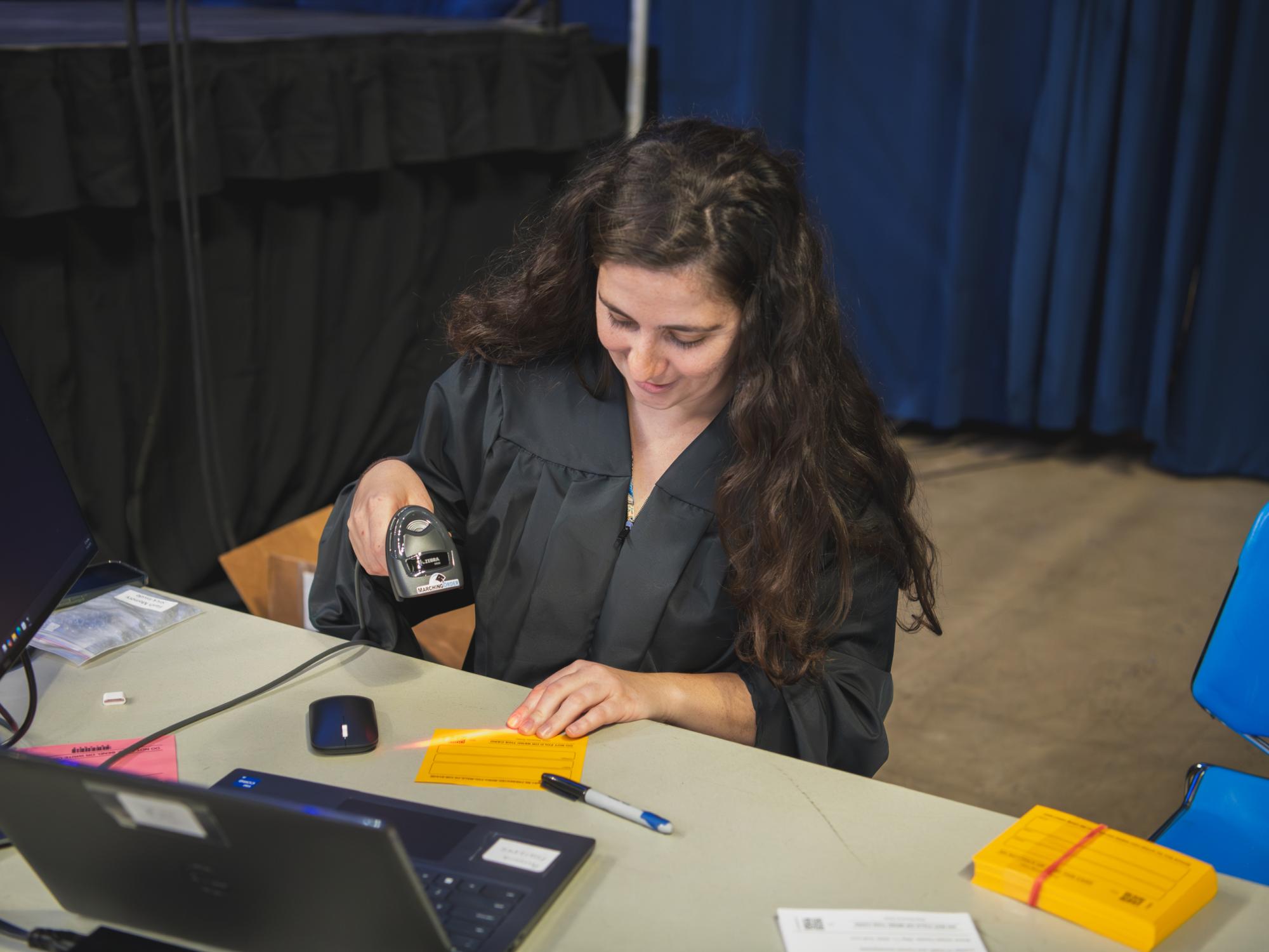A woman scans the code on a name card during a graduation ceremony