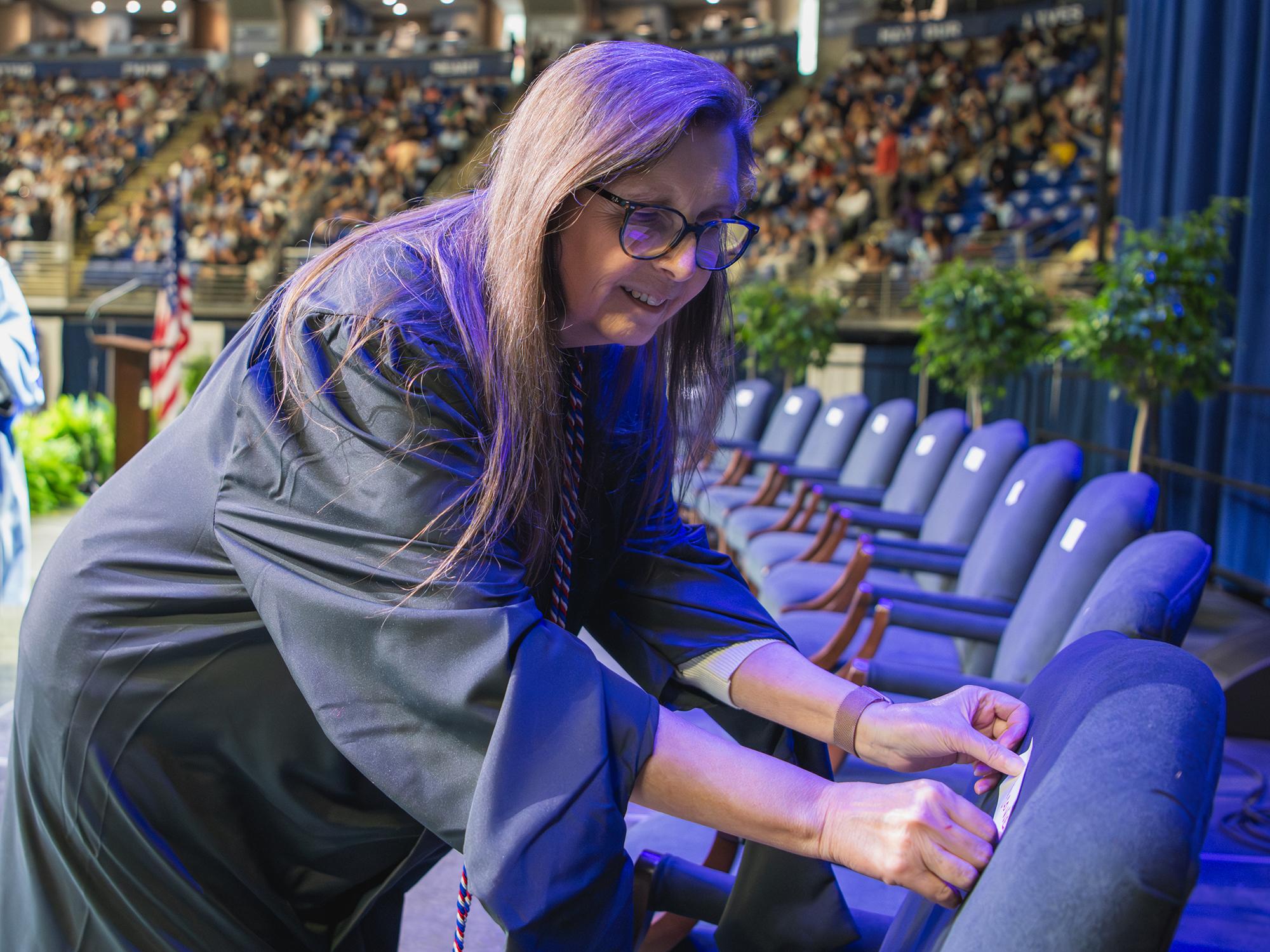 A woman places stickers onto a row of chairs on a stage