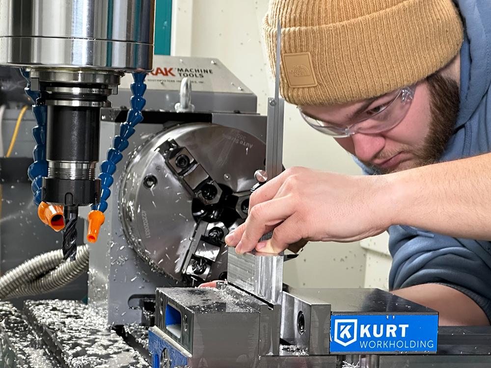 An individual wearing a hat and safety glasses uses a machine to cut metal.