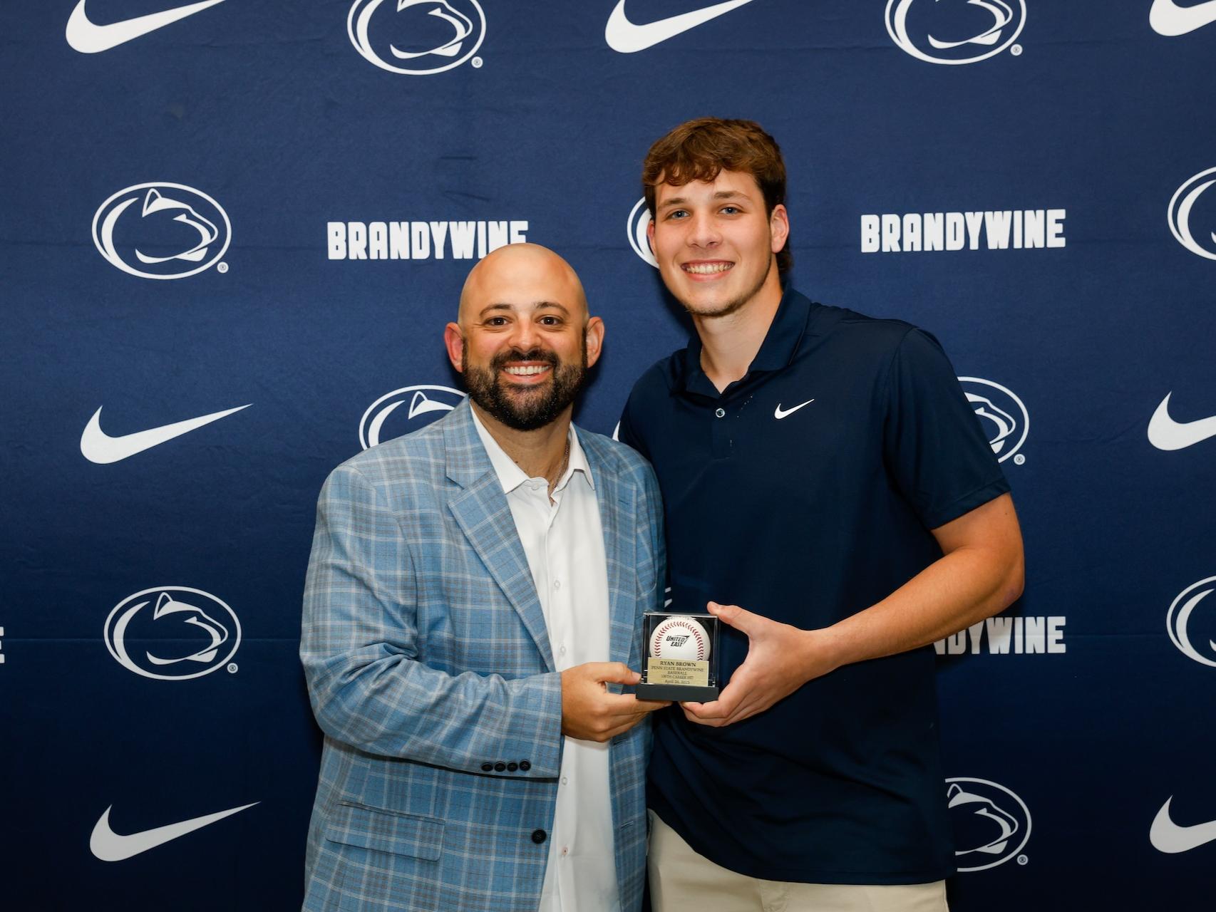 student holding baseball with coach