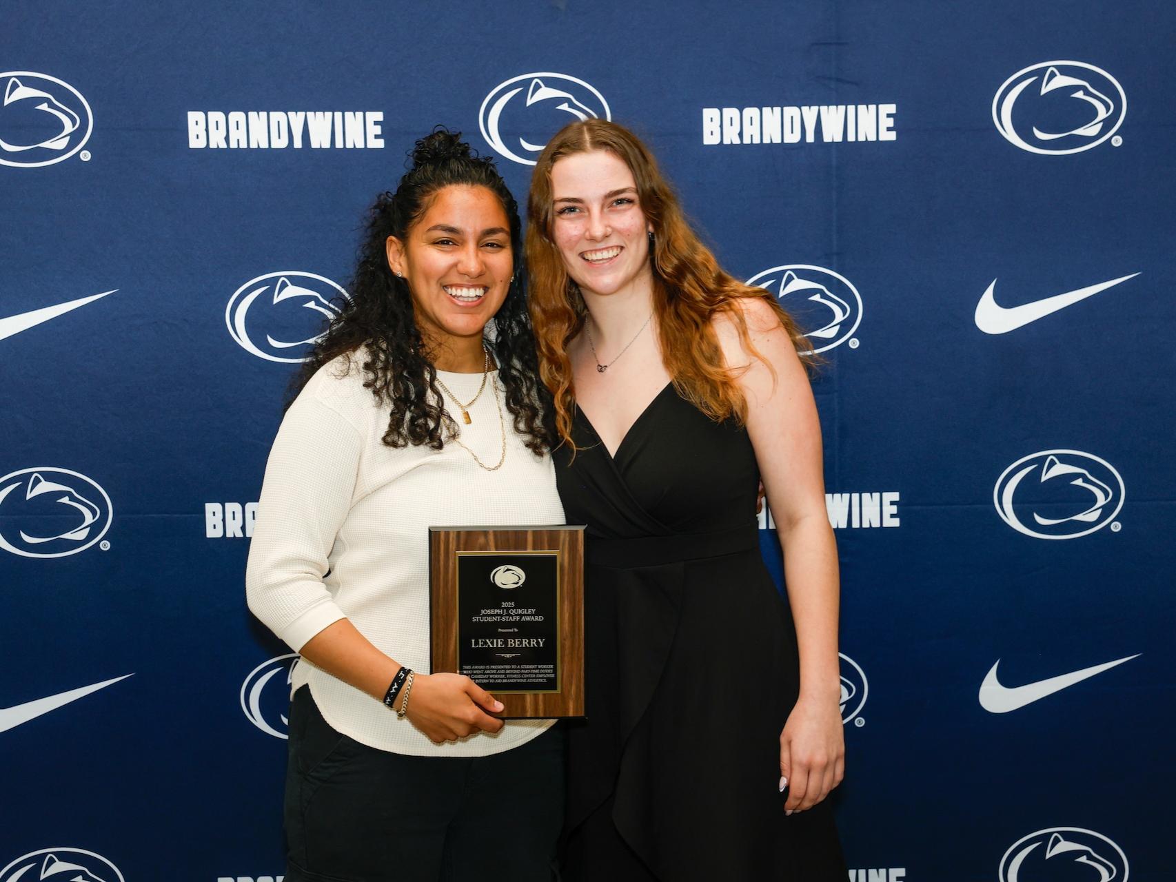 student and staff holding plaque