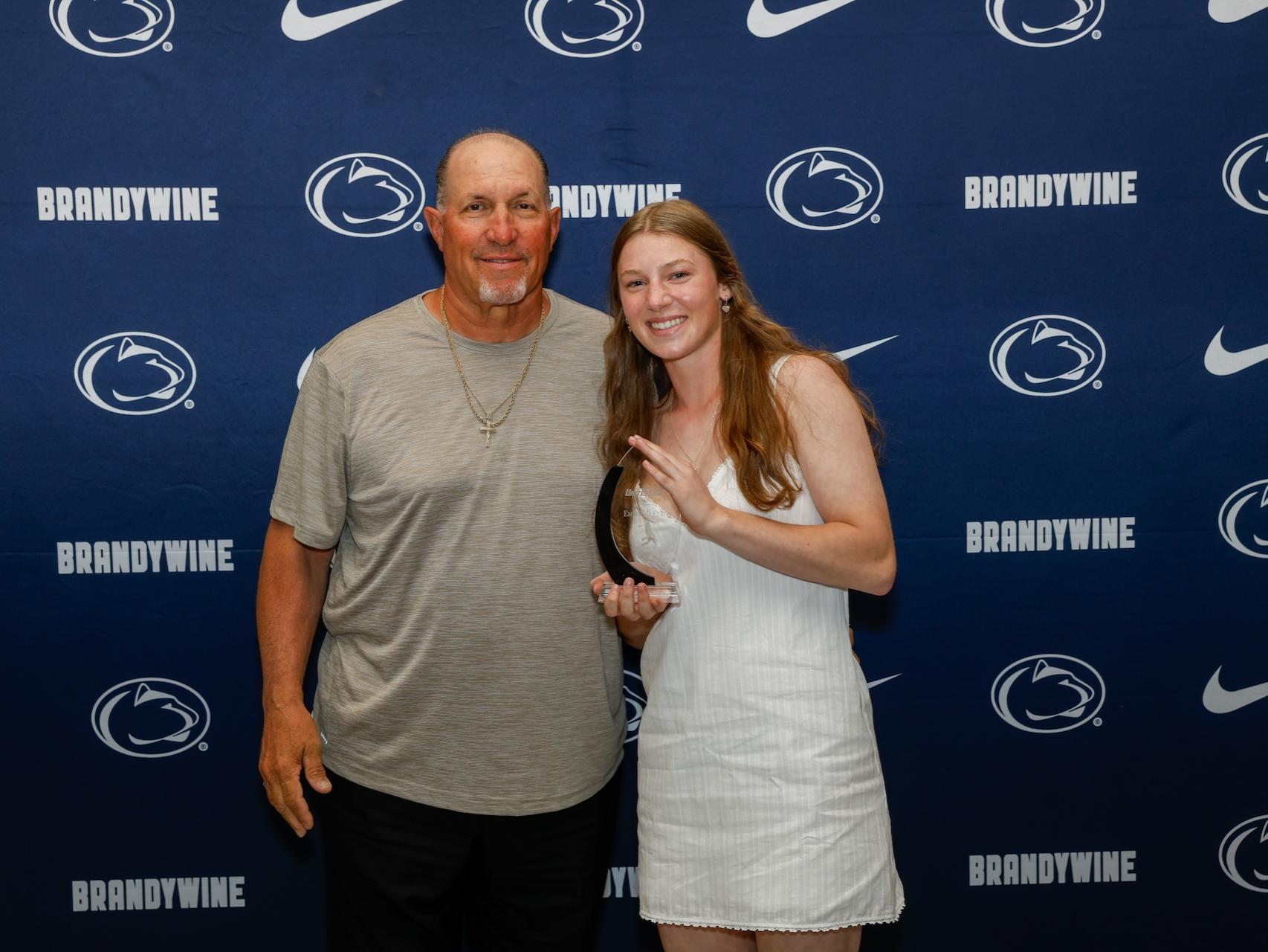student holding award with coach