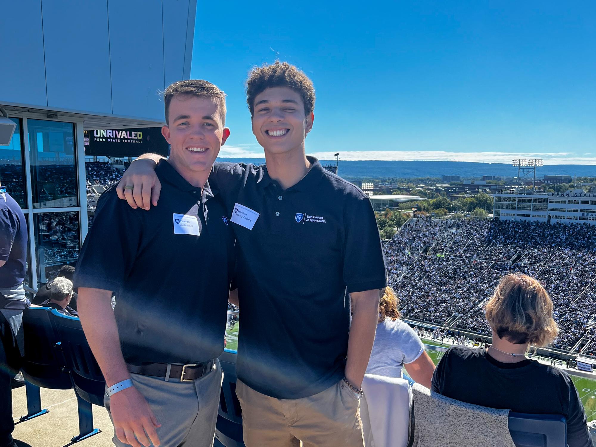 Dan Bransfield (left) with his arm around a friend standing outside a suite inside Beaver Stadium.