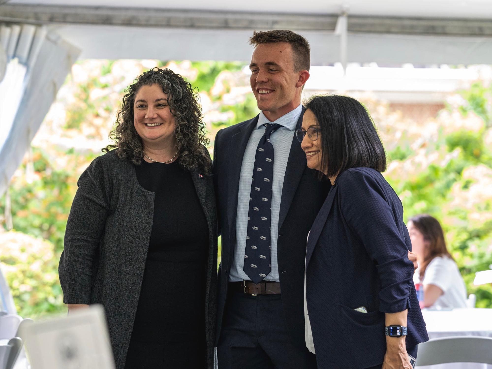 Dan Bransfield (middle) stands between a woman (left) and Penn State President Neeli Bendapudi (right) under a canopy outdoors.