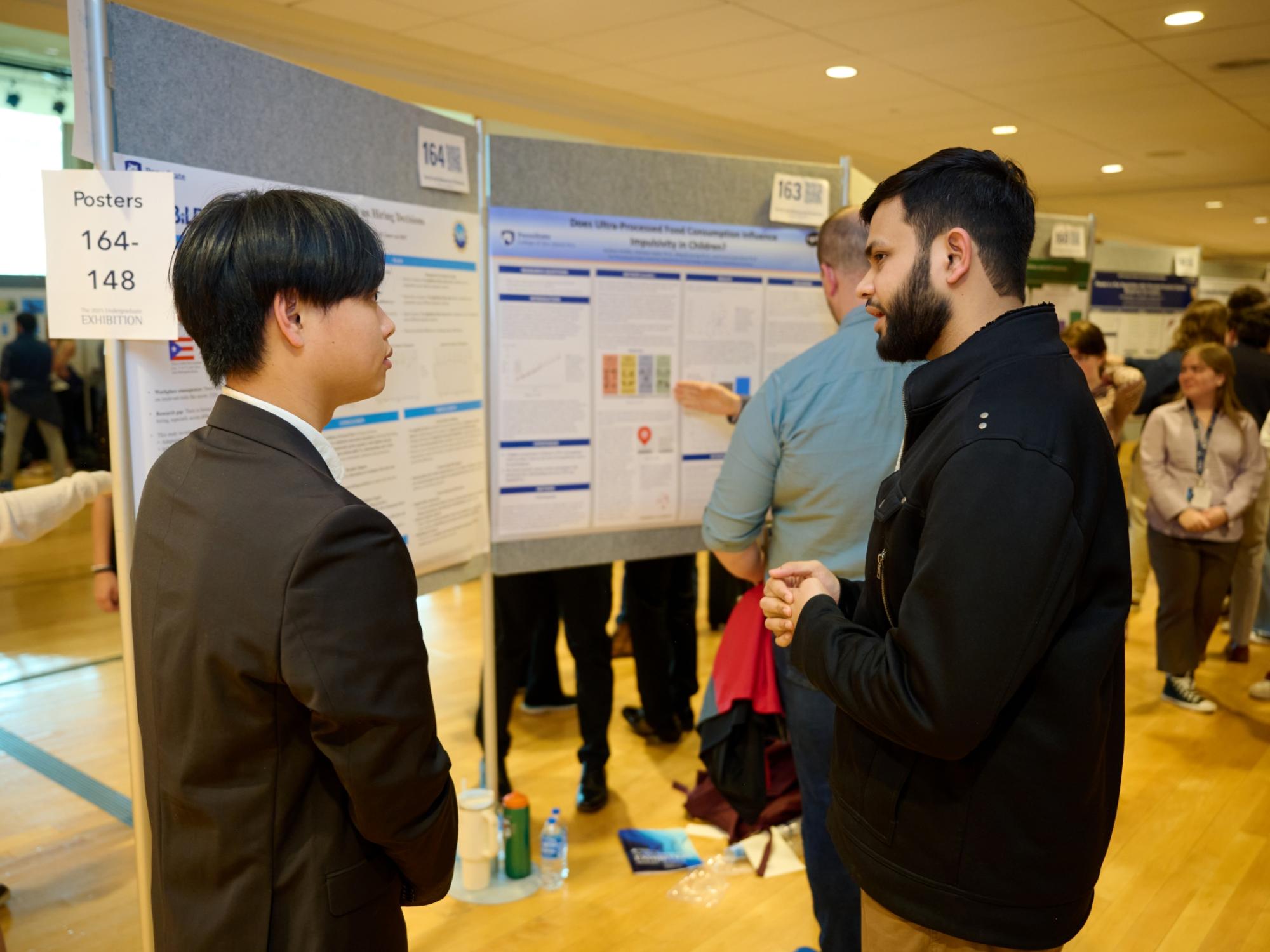 Two people talking in front of research poster