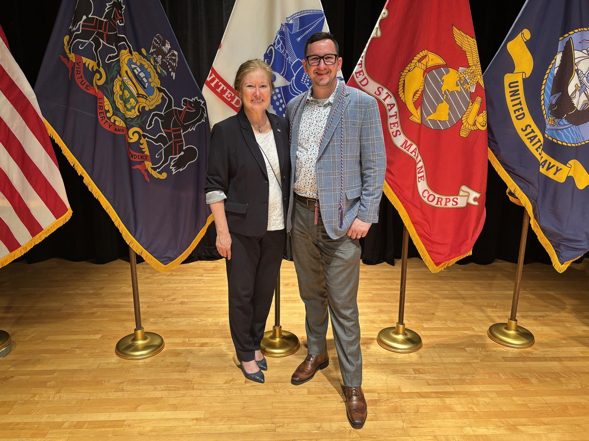 A man and woman stand in front of a group of flags.
