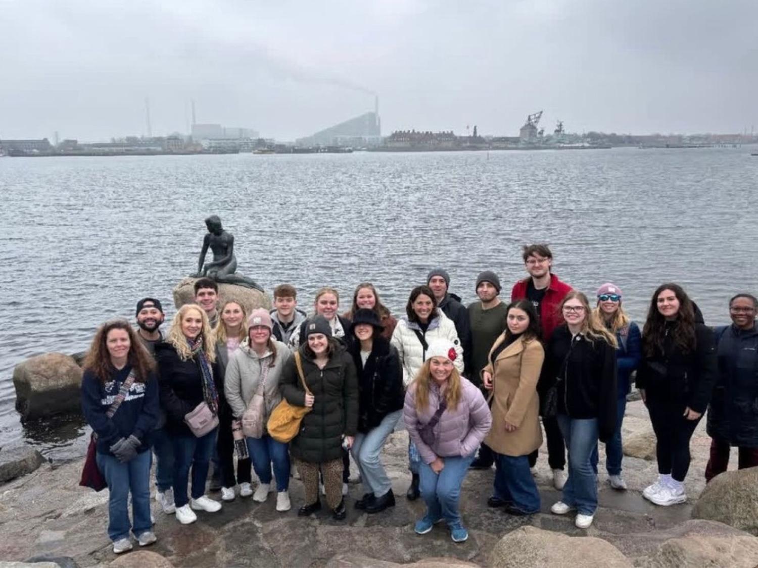 A group of students pose at a waterfront