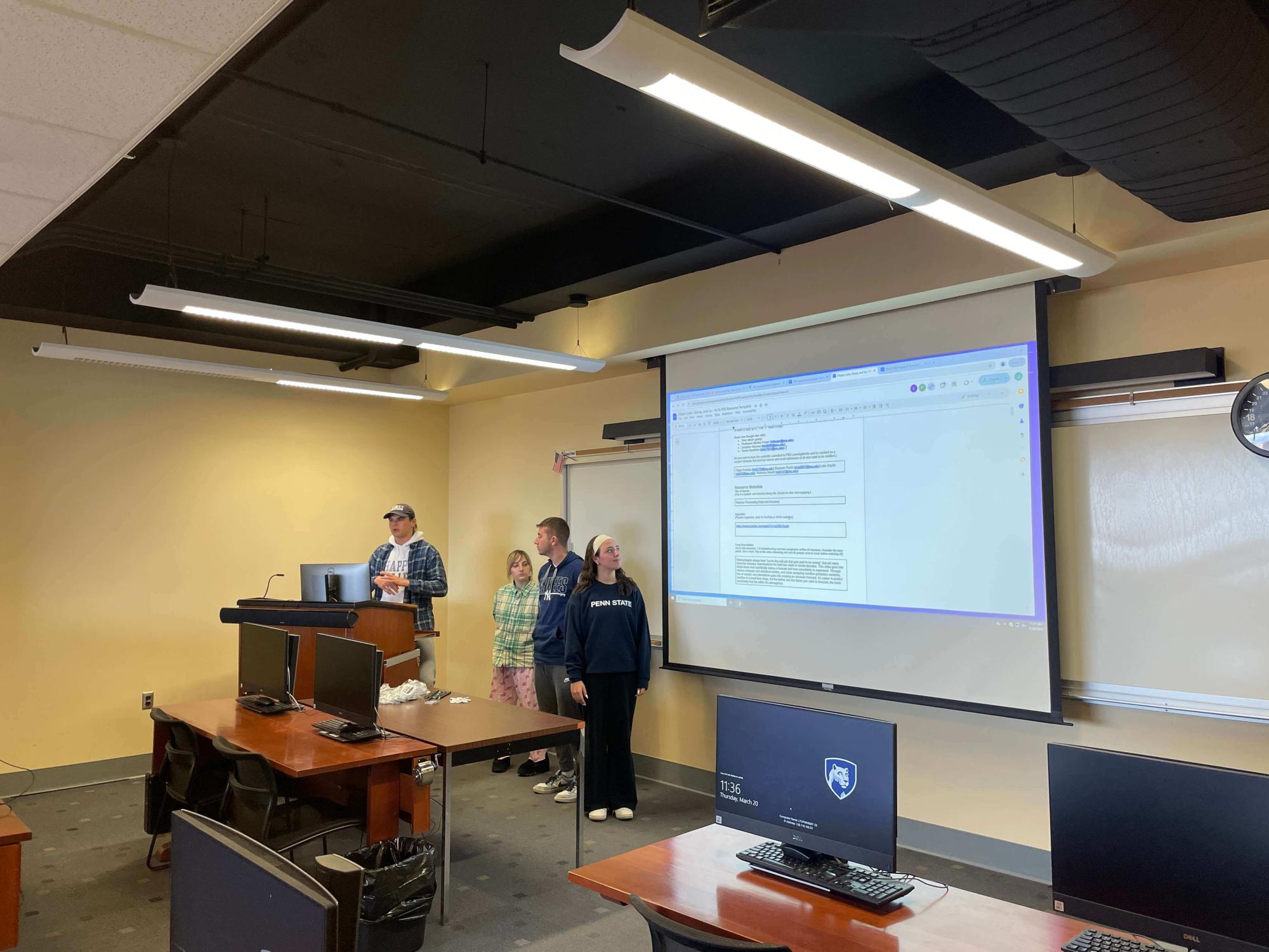 Four students giving a presentation in the front of a classroom