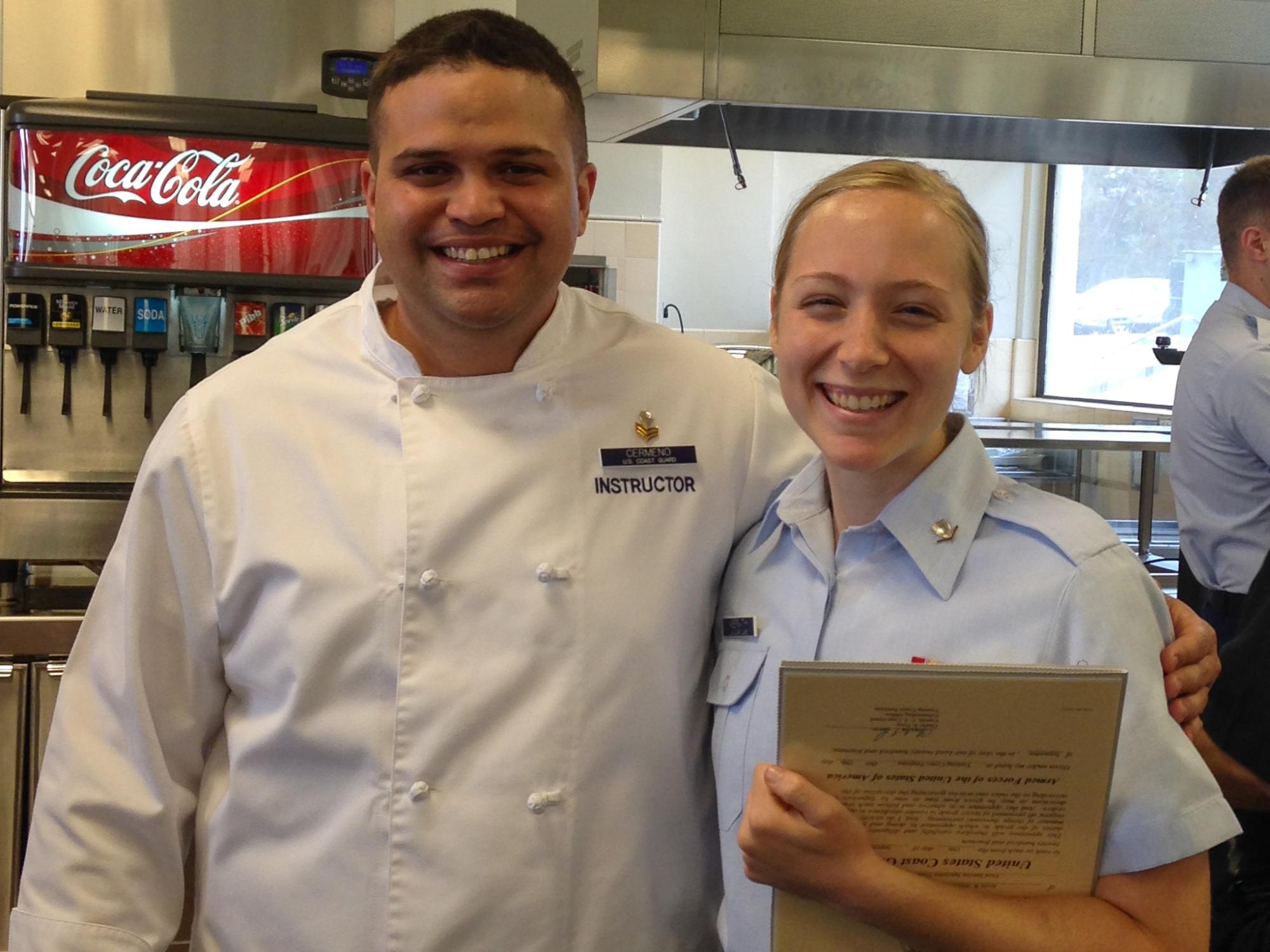 Jessie Wolfen in her Coast Guard uniform poses with an instructor wearing a chef’s uniform. 