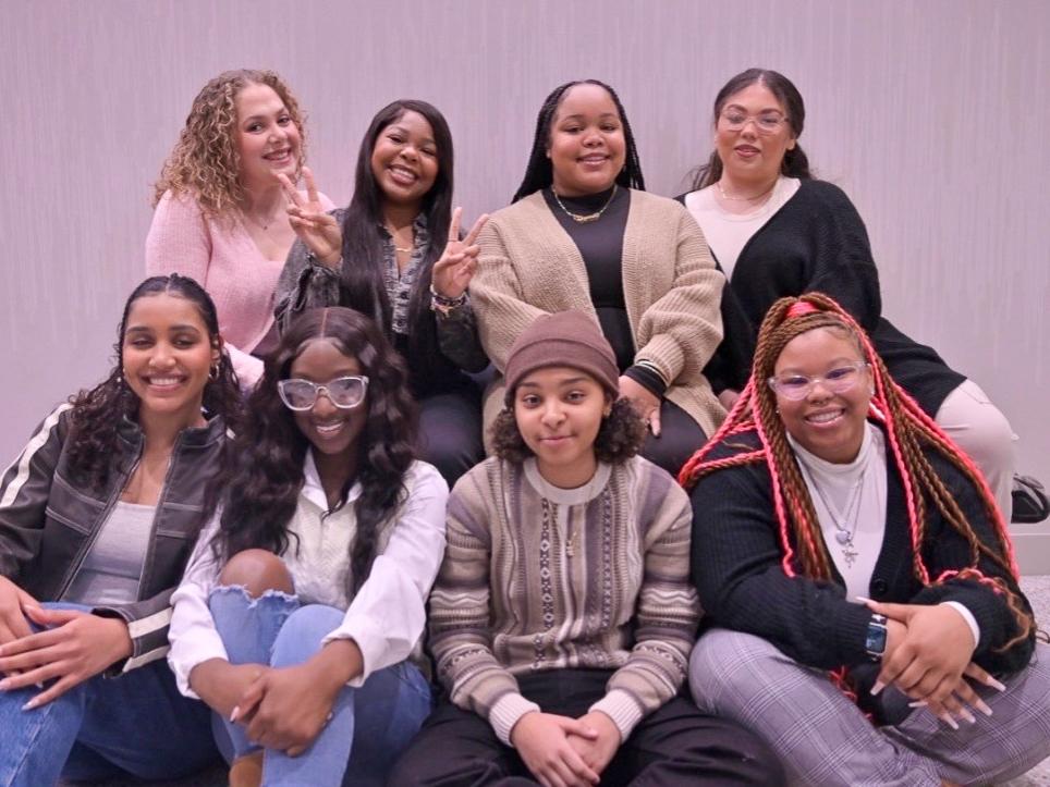 A group of students sit smiling for a photoshoot.