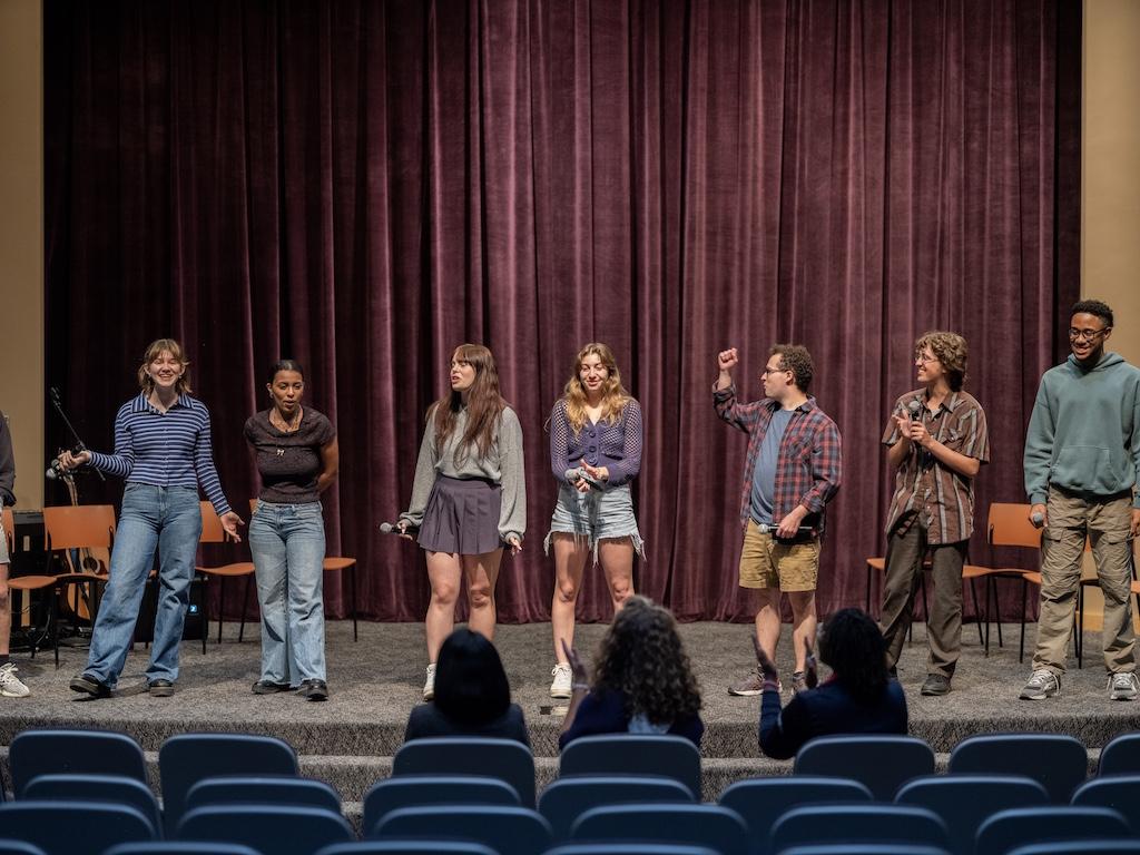 Students in the Results Will Vary* cast of the theatre production stand in a line on stage.