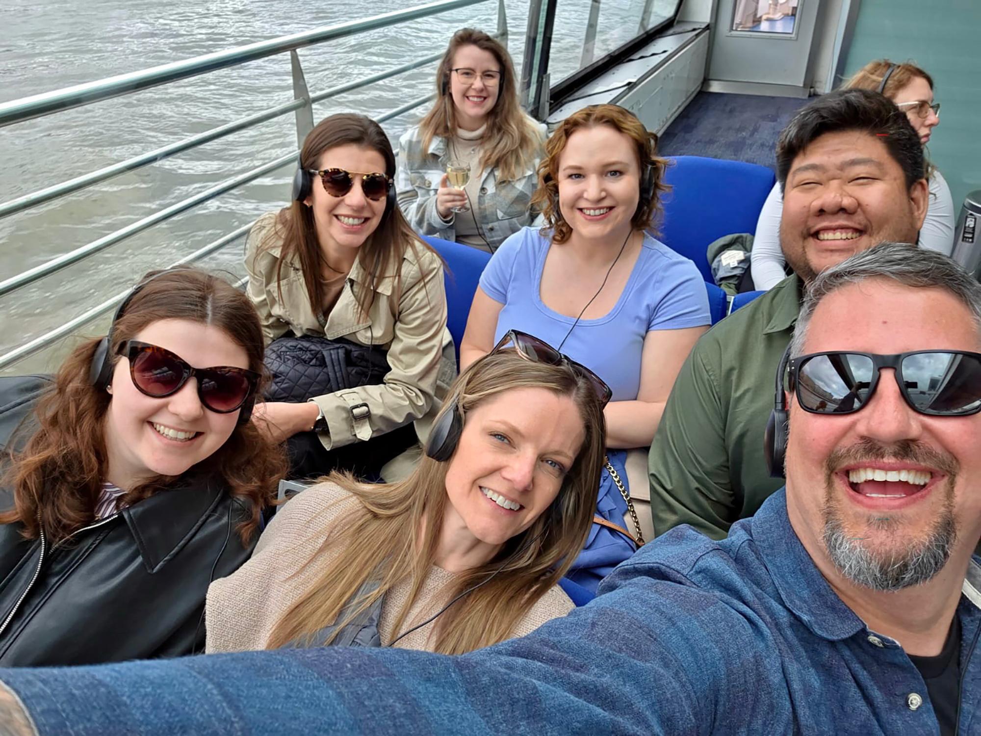 Eight people pose for a selfie photo on a boat.