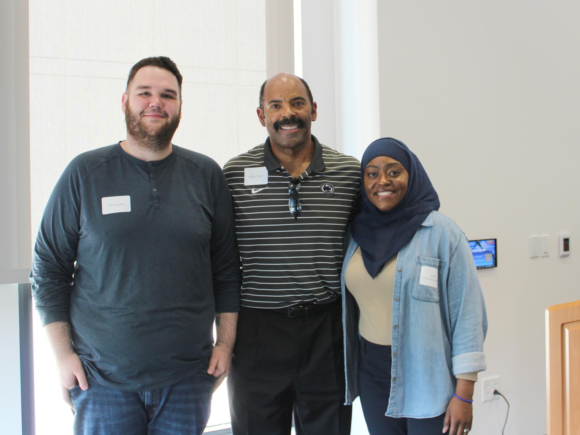 Three people stand in a row for a photo.