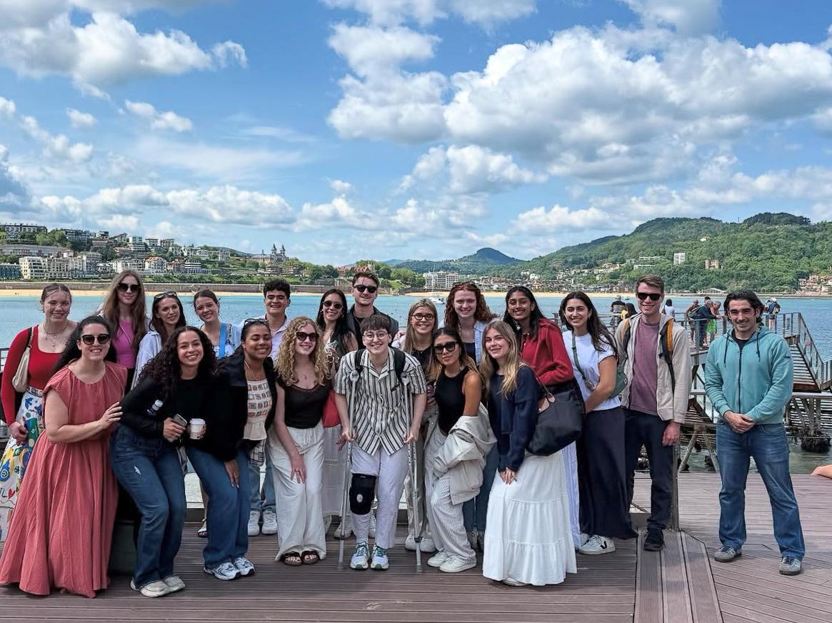 Diana Lopez (sixth from the left in the back row) poses with a group of students before a pier, in San Sebastian, Spain.