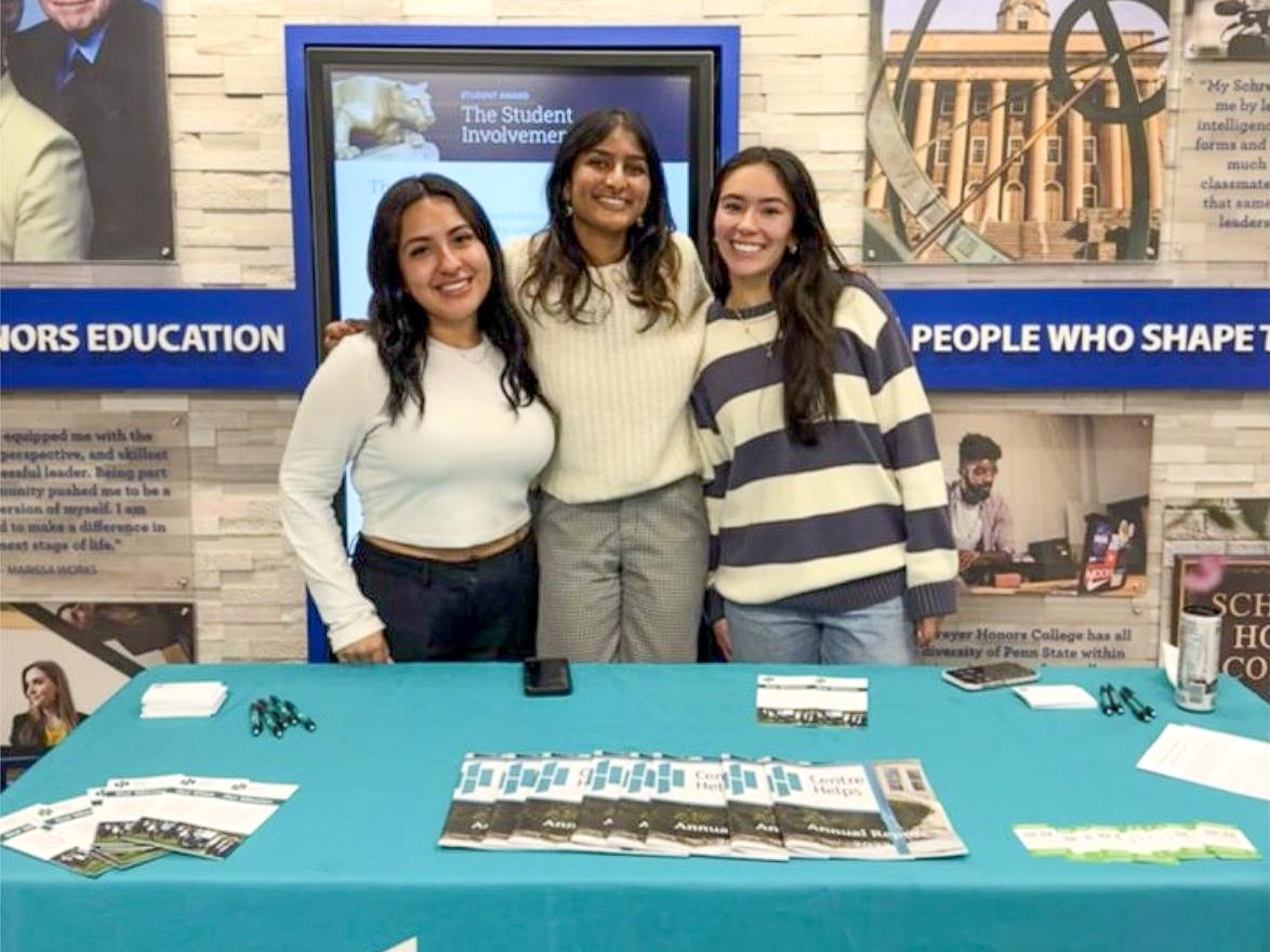 Diana Lopez (right) stands with two other women behind a table that reads Centre Helps.