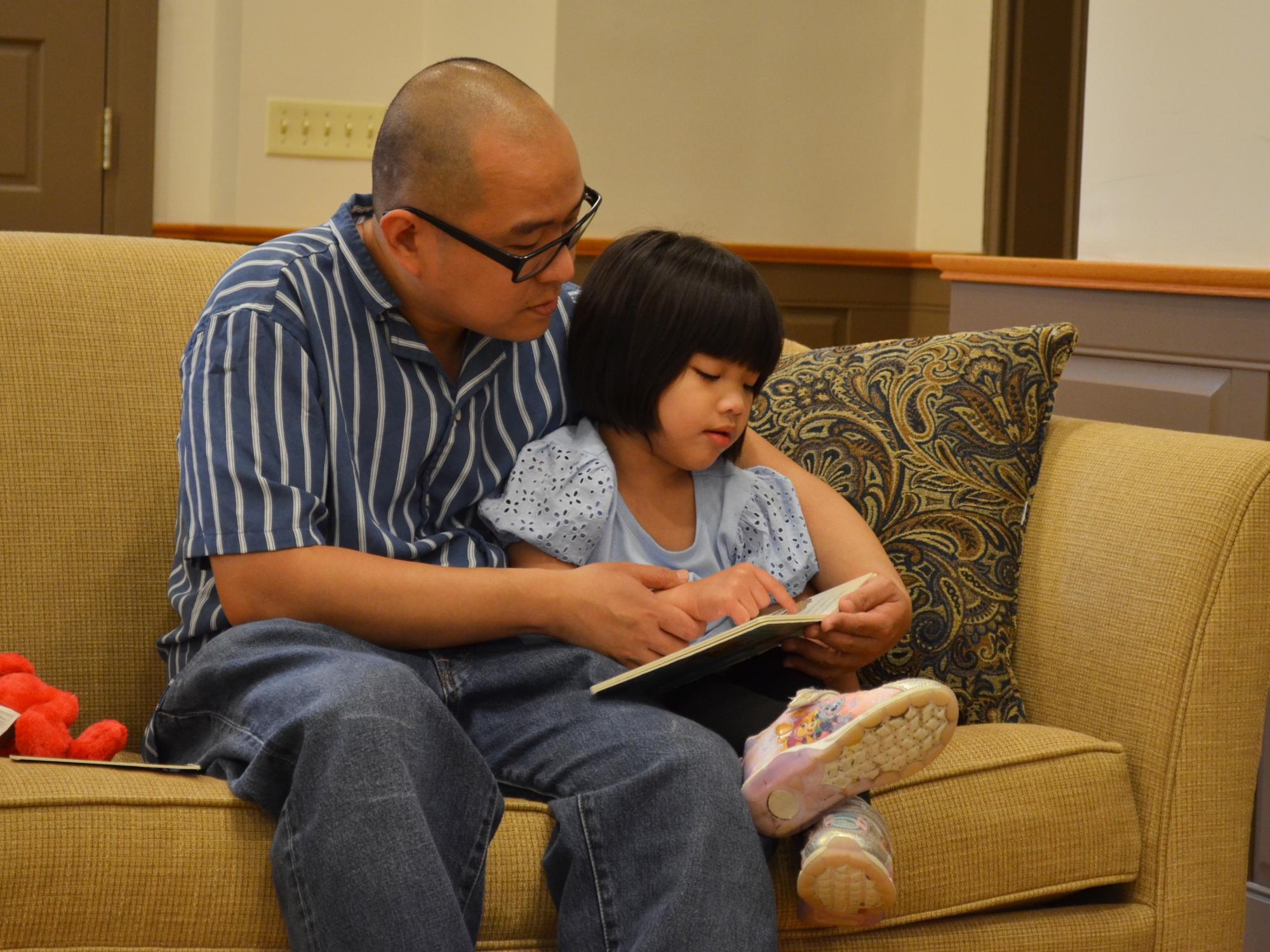 Mark and Mabel Ramos reading a board book on a couch