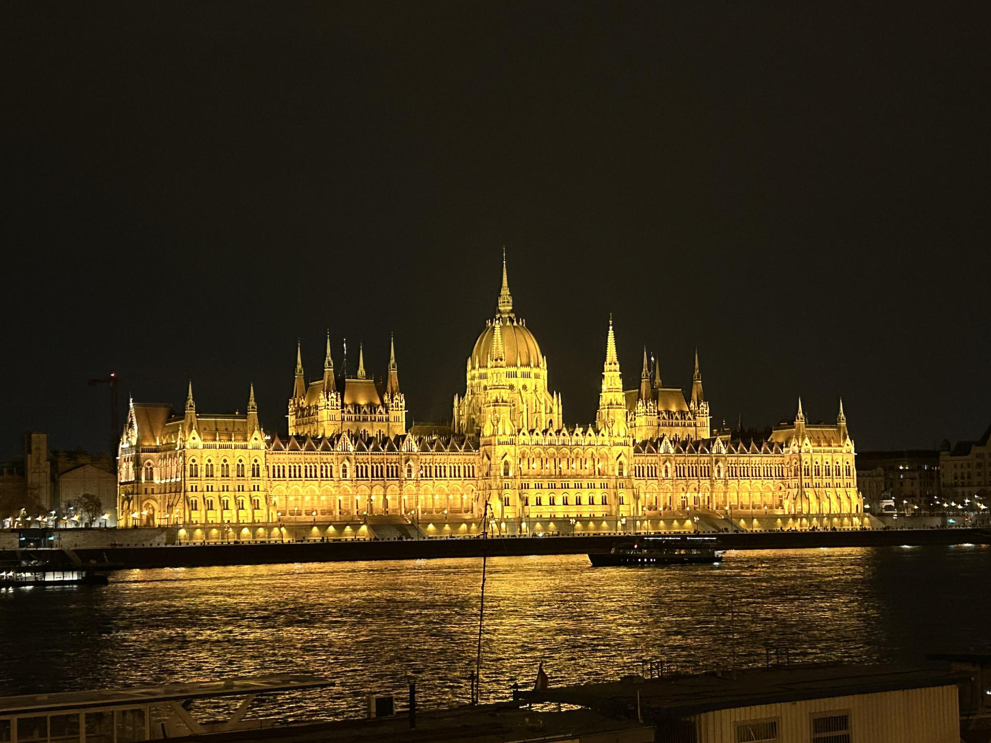 An old-style European building is illuminated near a river.