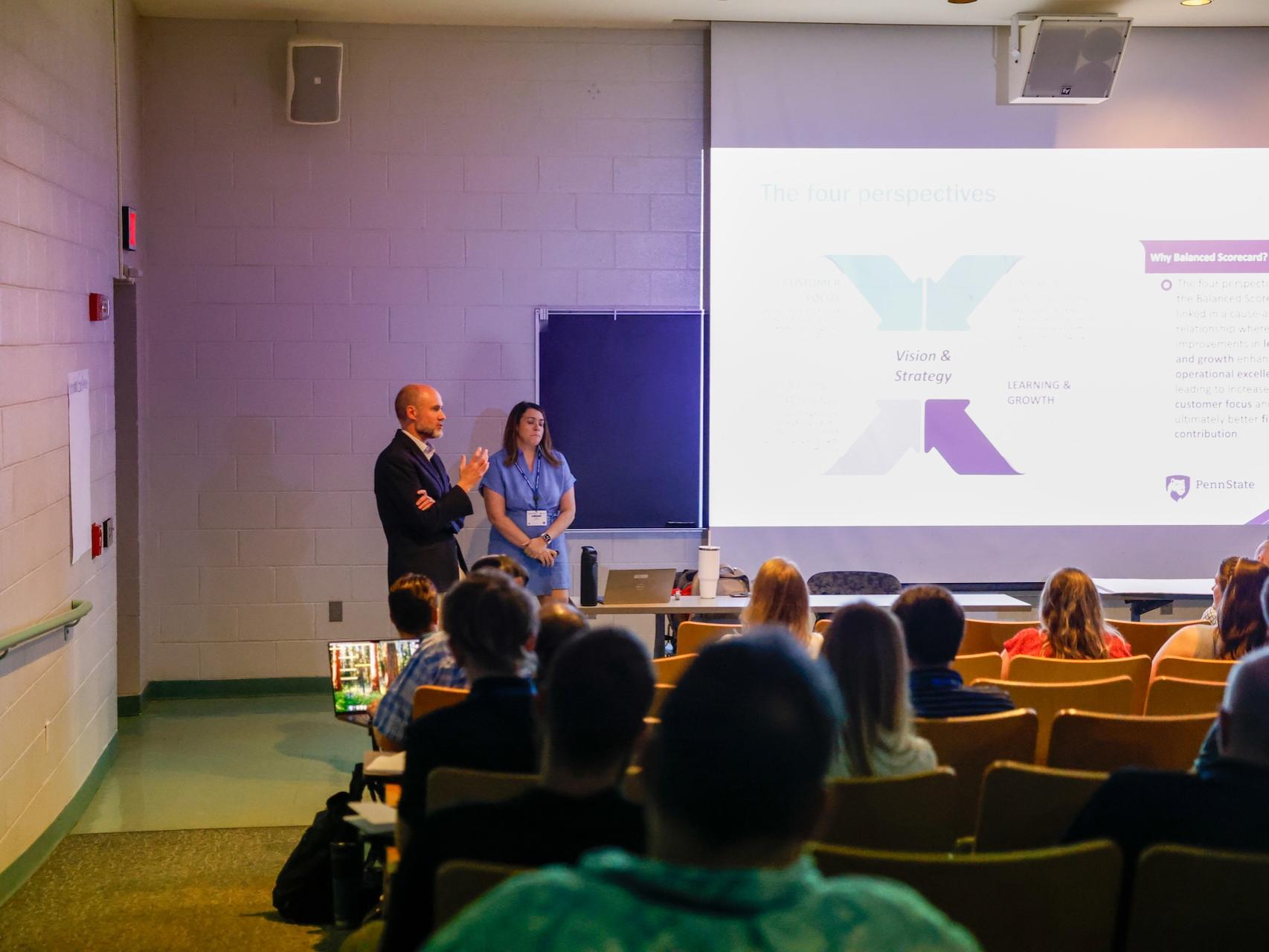 people speaking in auditorium in front of a crowd