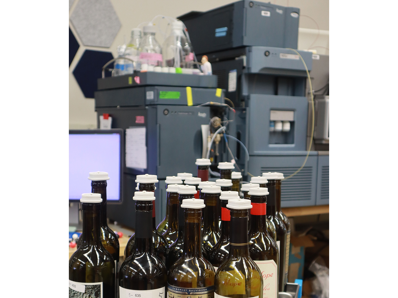 Wine bottle tops with a mass spectrometer in the background