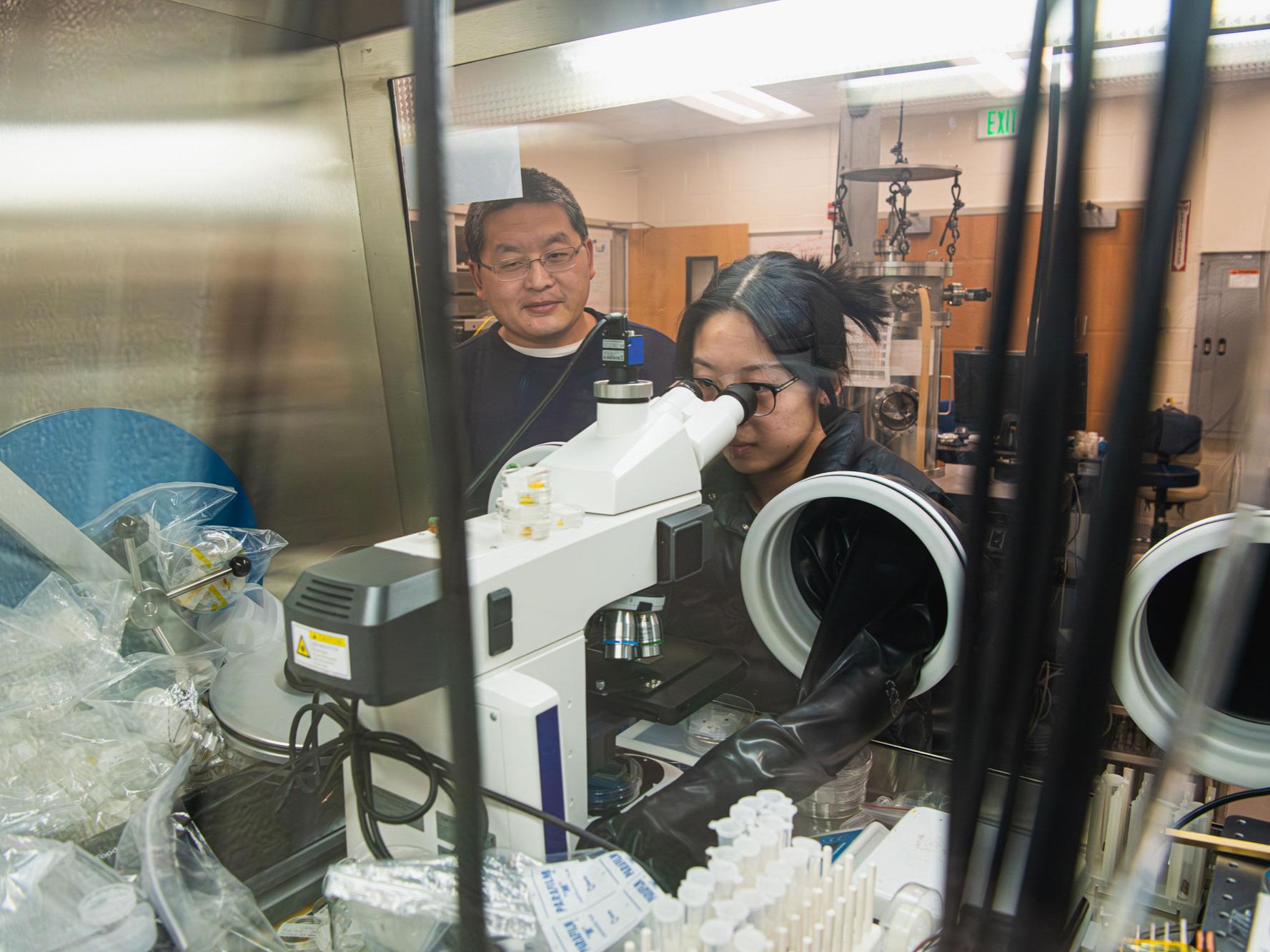 Annie Wang works in fume hood while Cui-Zu Chang observes