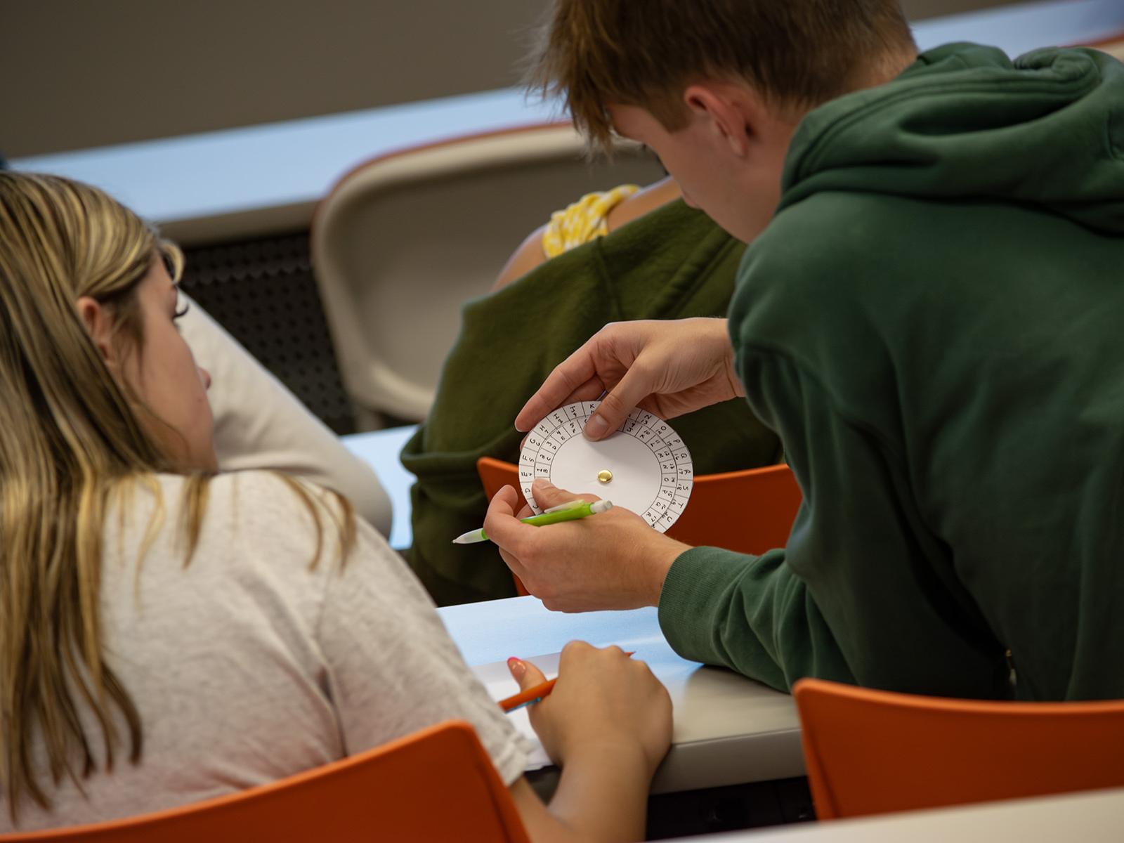 Students look at a cipher wheel during a STEM activity